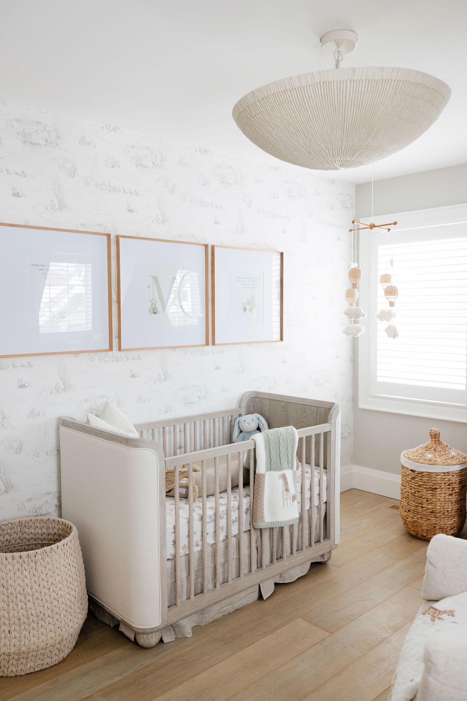 Modern nursery with white crib, woven baskets, and minimalist wall art in a bright airy room.