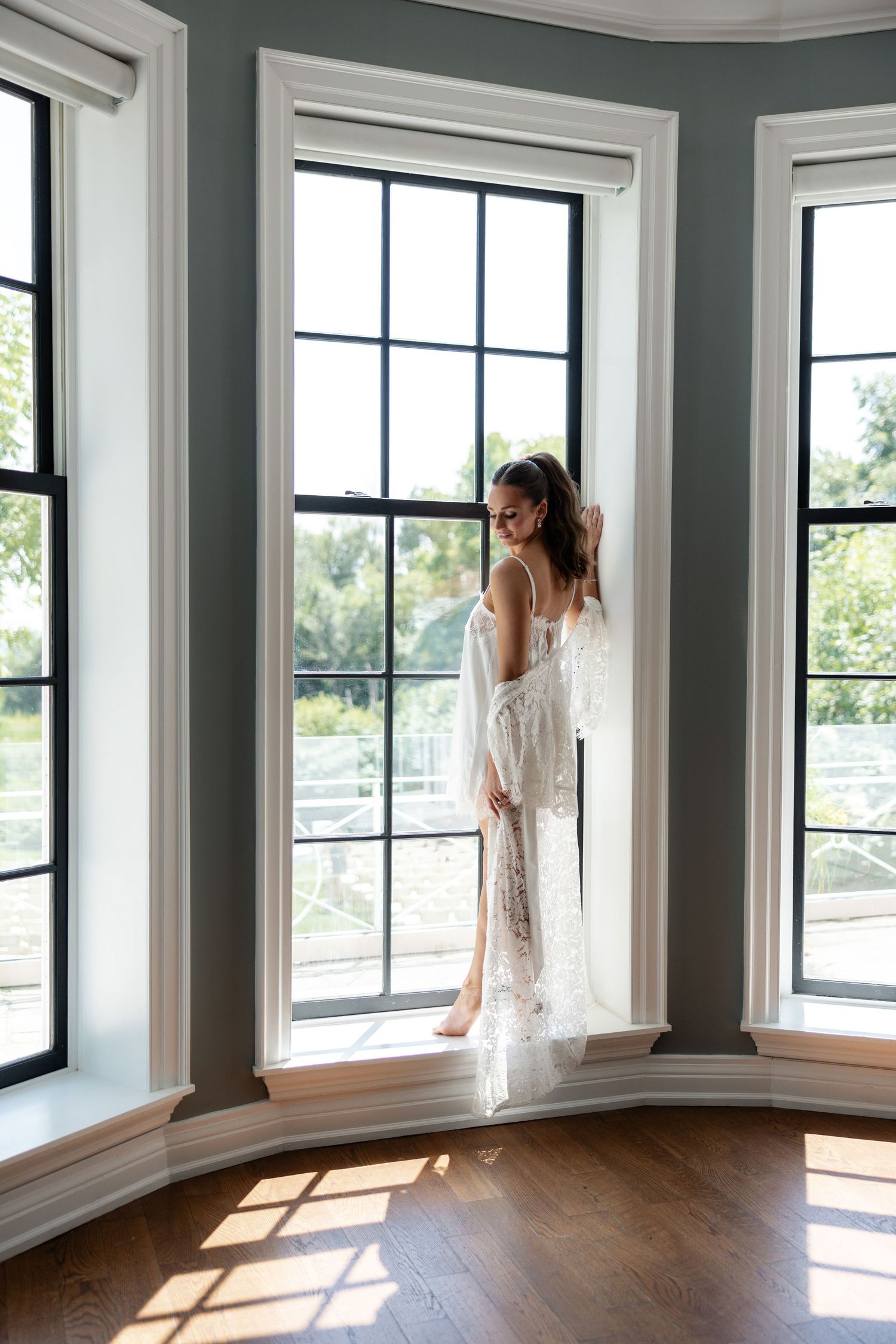 Sunlight streams through windows in an elegant room with dark walls and wood floors.