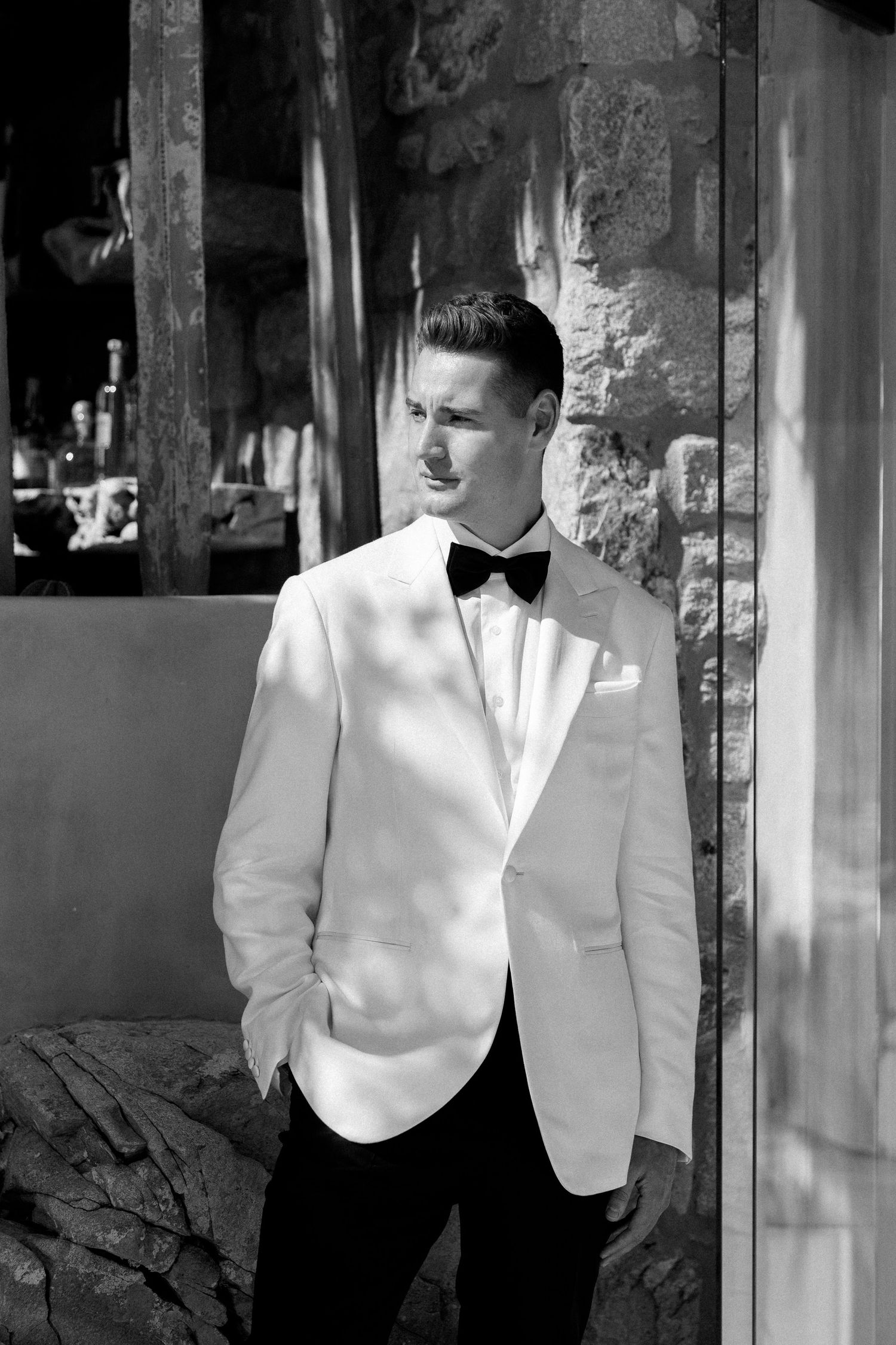 Black and white photo of a groom in formal attire preparing for the ceremony.