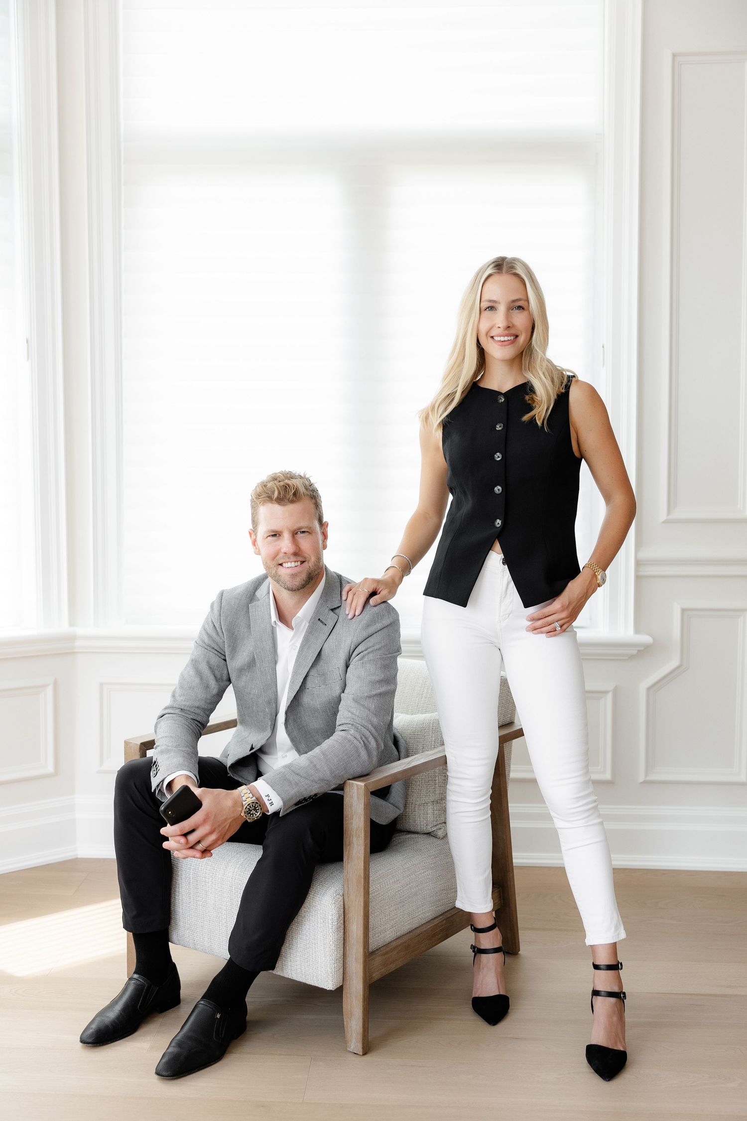 Business duo posing in modern office setting with coordinated formal attire.