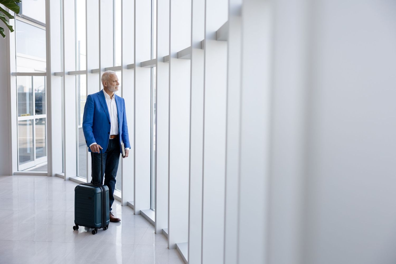 Bright minimalist corridor with floor-to-ceiling windows and rolling luggage.