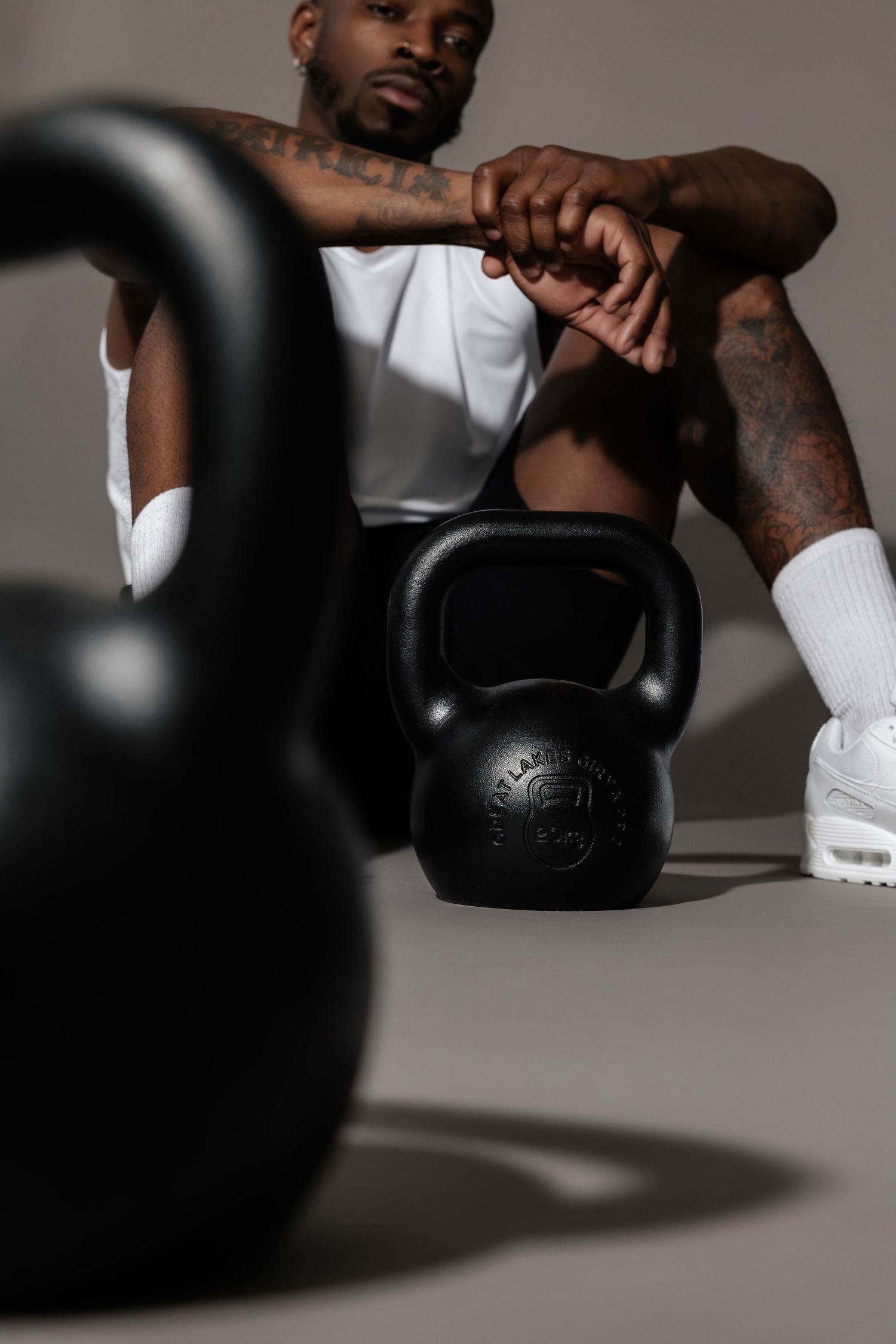 Athletic person in white tank top performing kettlebell exercises in studio setting.