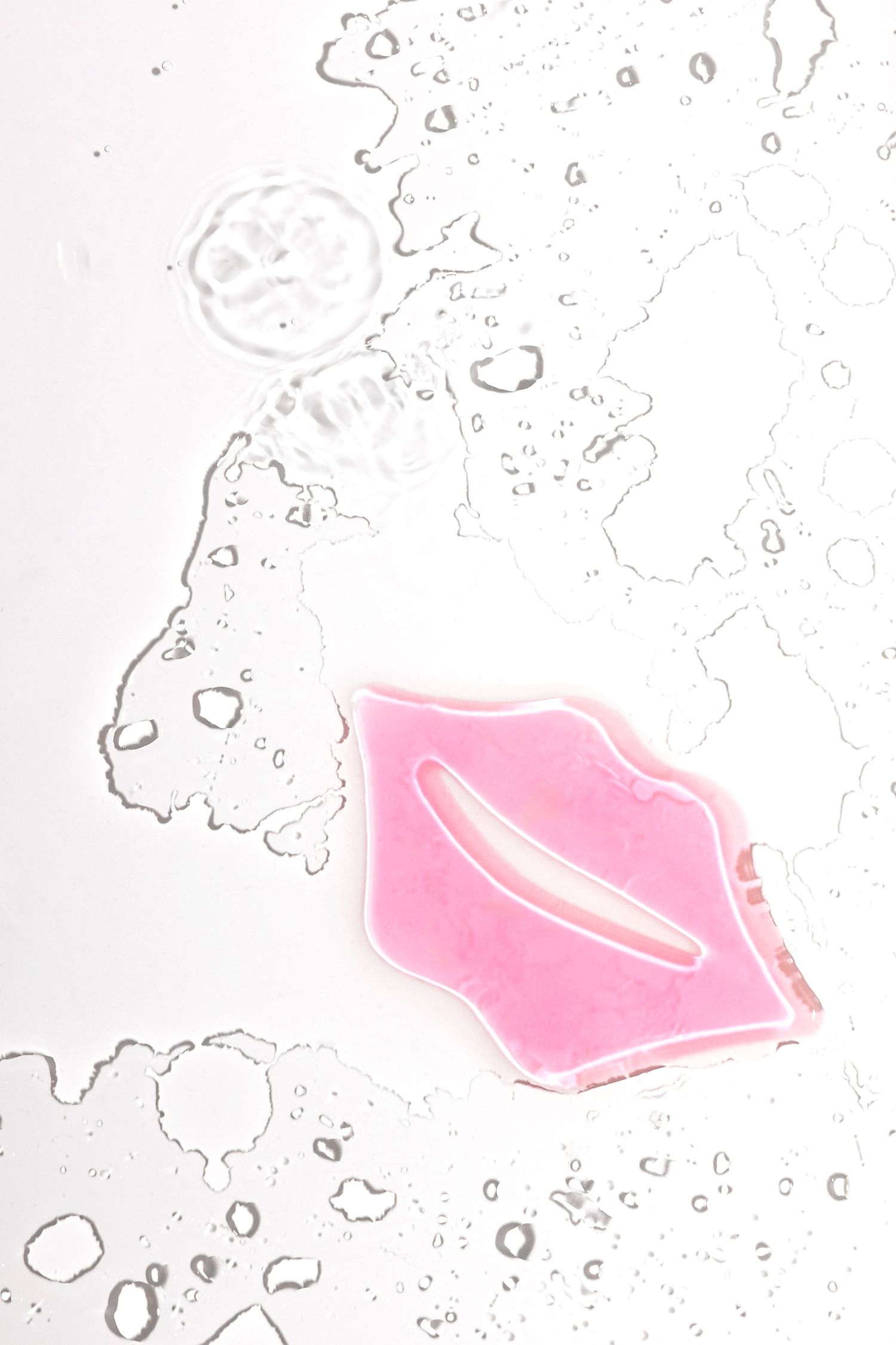 Pink lip shape design with water droplets on white minimalist background.
