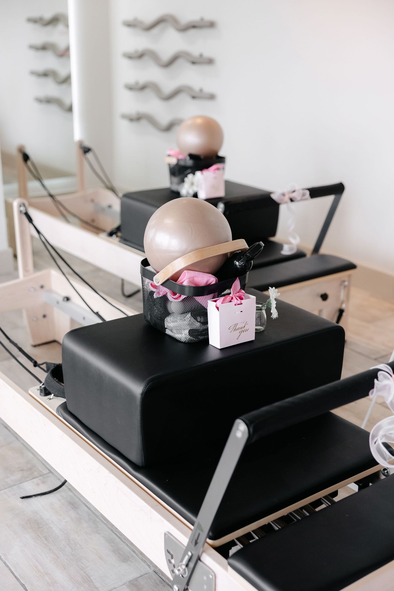 Pilates reformer machines with pink accessories in a modern fitness studio.