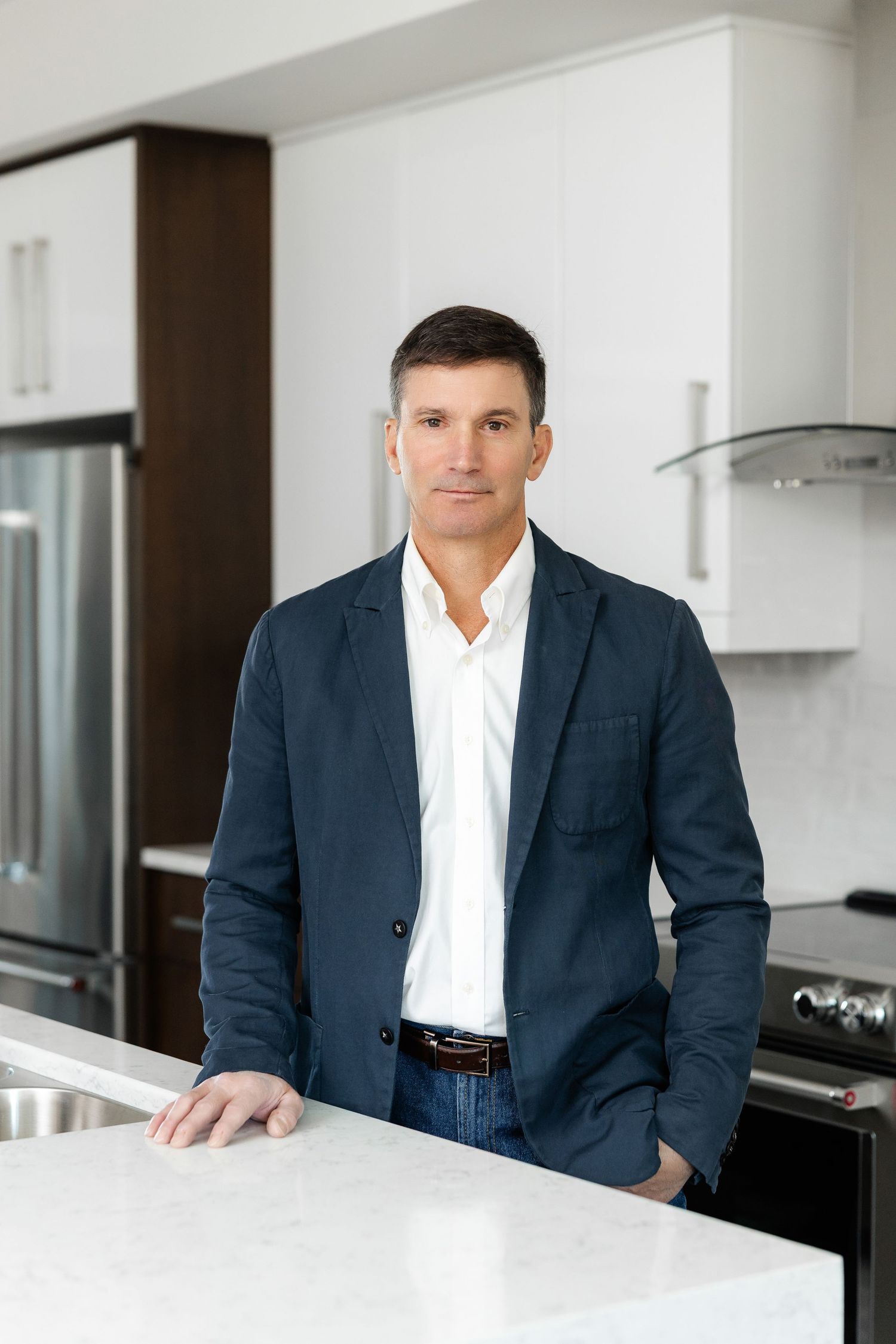 Professional in business attire standing at kitchen counter.