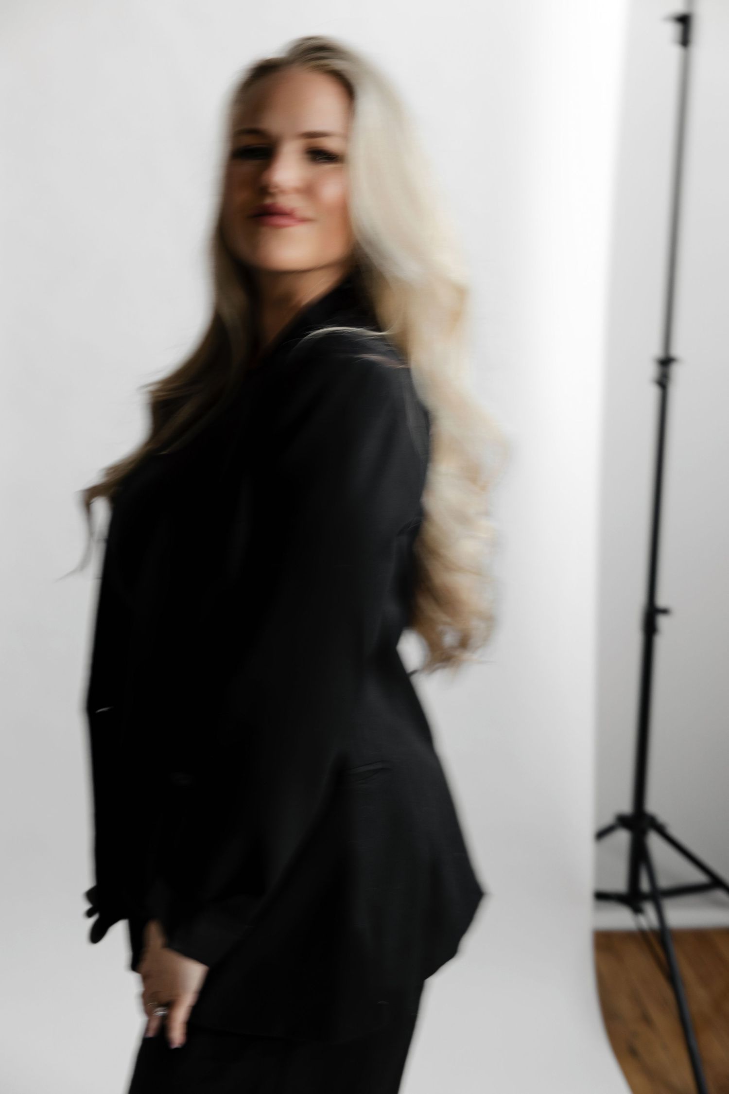 Artistic motion blur portraits in black outfit against white studio backdrop.
