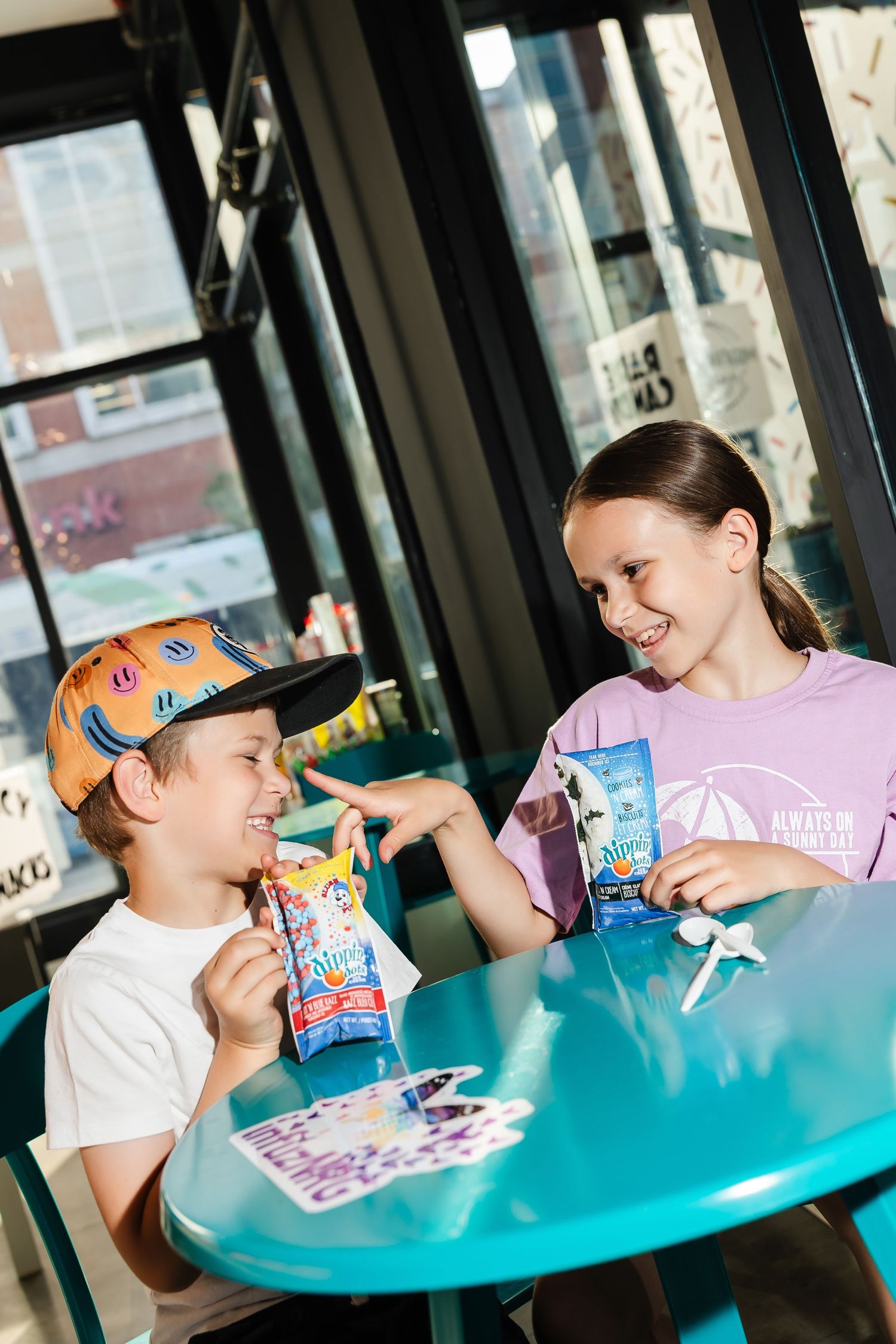 Kids enjoying snacks together at a turquoise table.