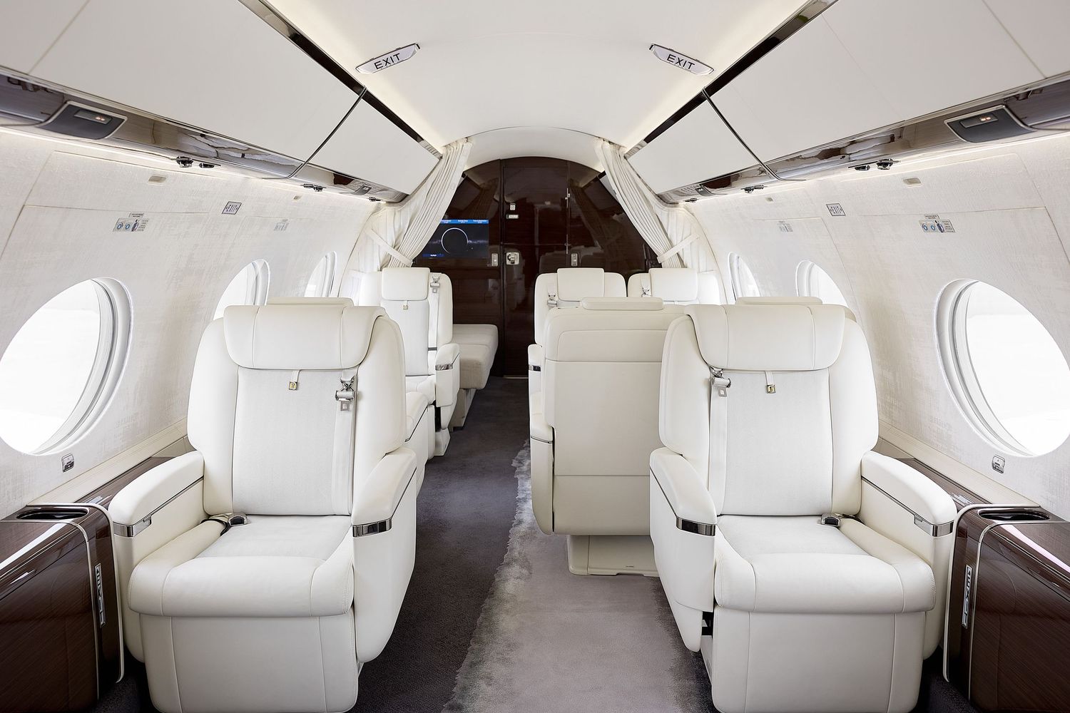 Interior view of a luxury private jet cabin with white leather seats and modern amenities.