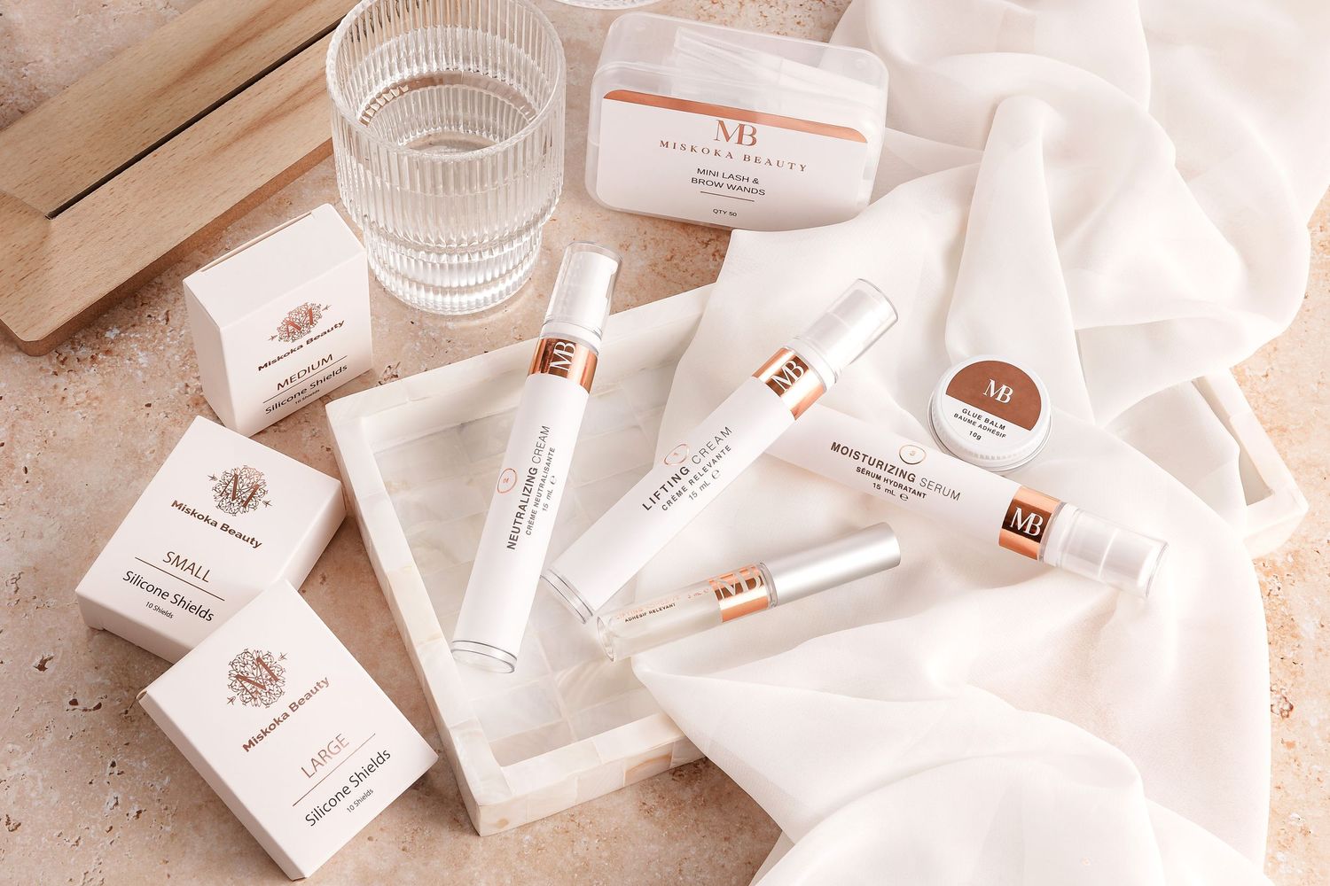 Collection of elegant white skincare product packaging and glass containers on beige surface.