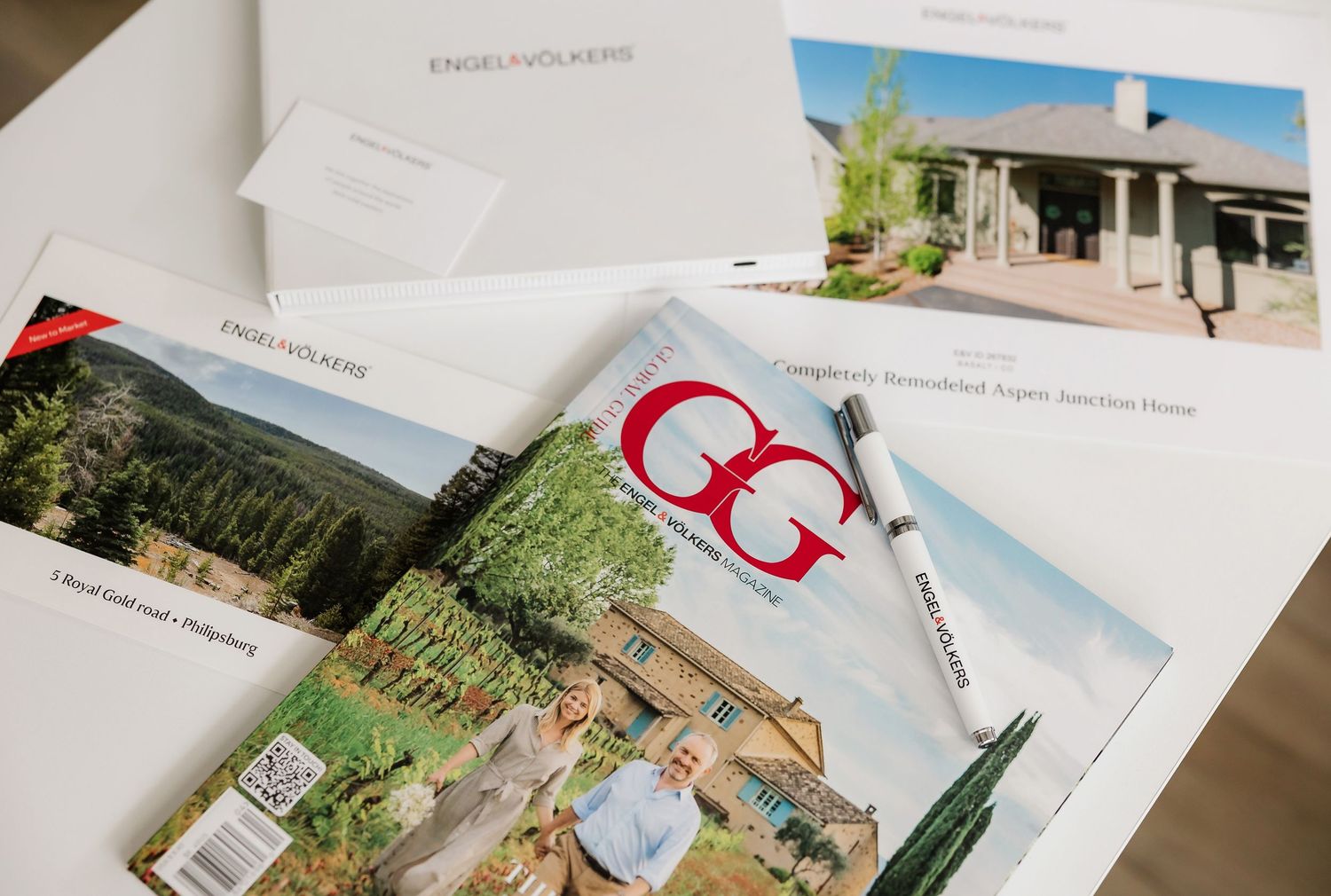 Collection of printed real estate property photos and marketing materials laid out on white surface.