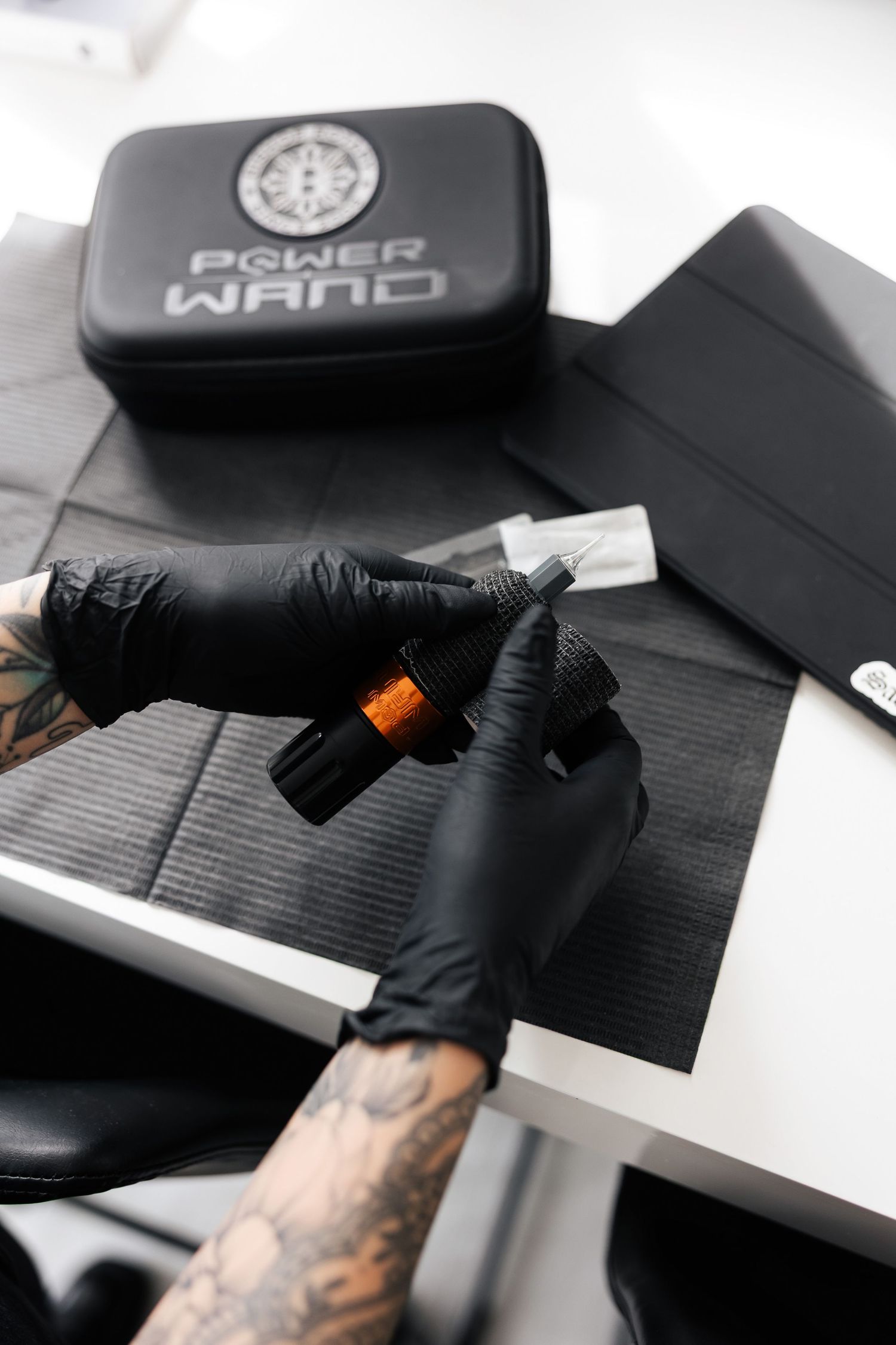 Tattooed hands in black gloves working with packaging materials.