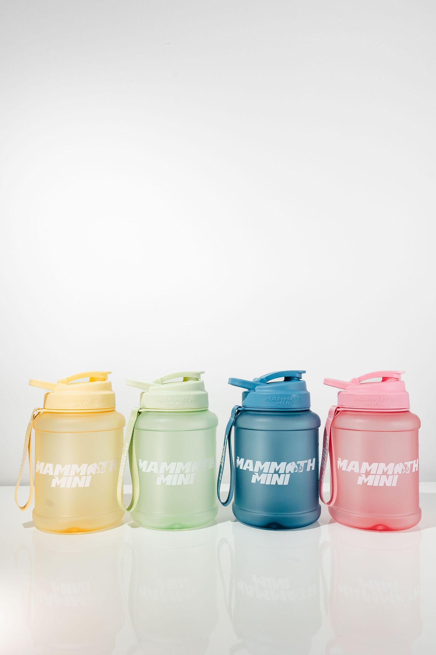 Colorful plastic drink containers in yellow, green, blue and pink arranged in a row on white background.