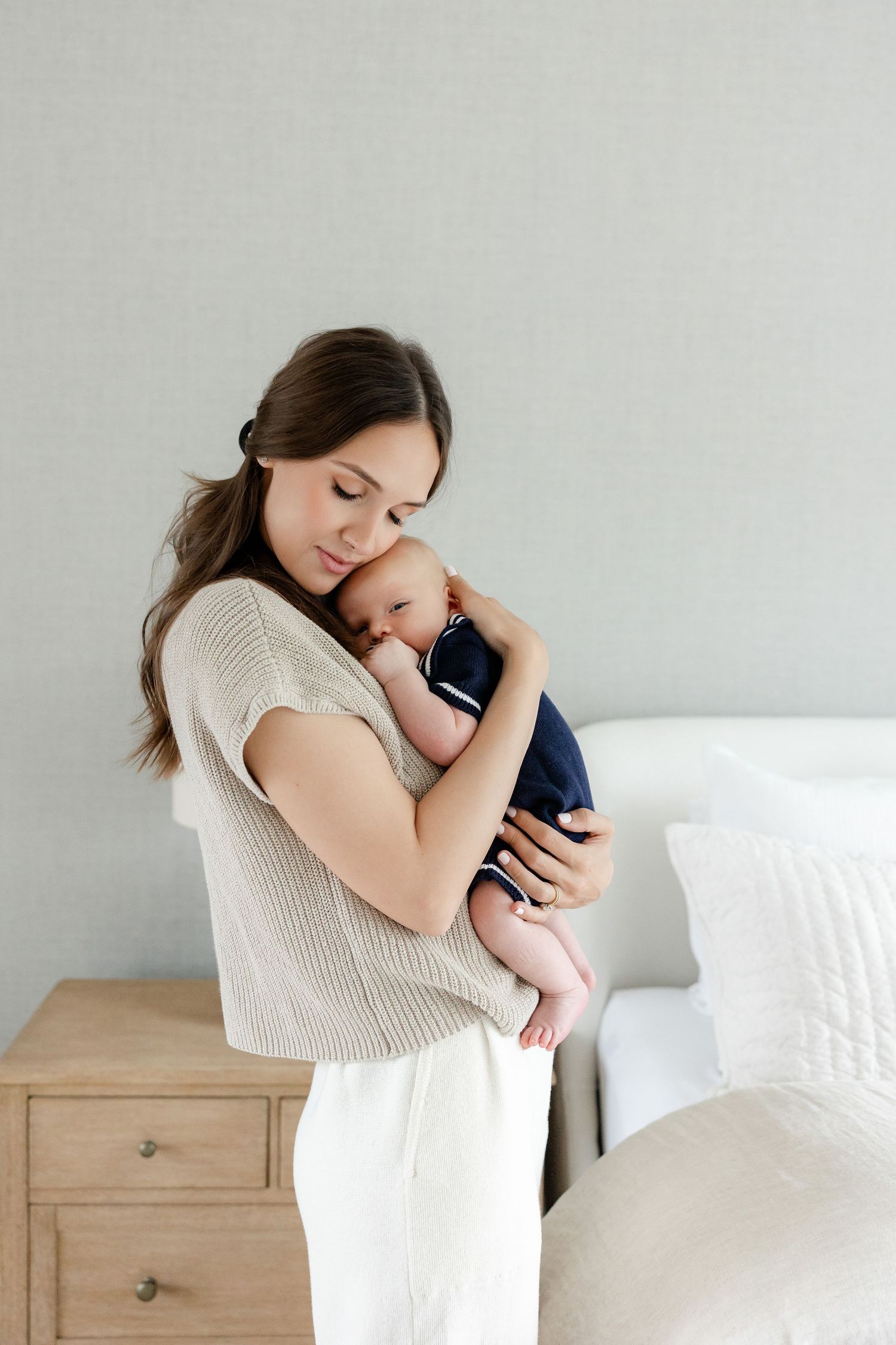 Intimate bonding moment with baby in a bright minimalist bedroom setting.
