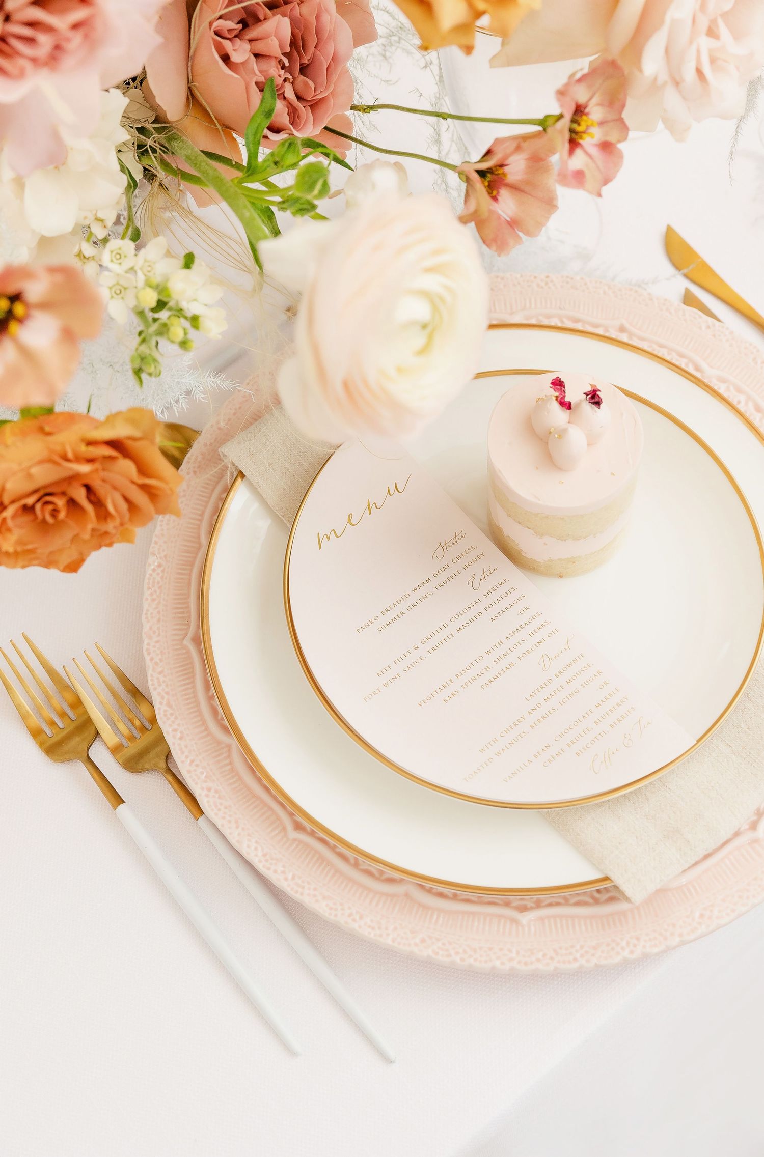 Romantic table decor with pink and peach roses above delicate place settings.