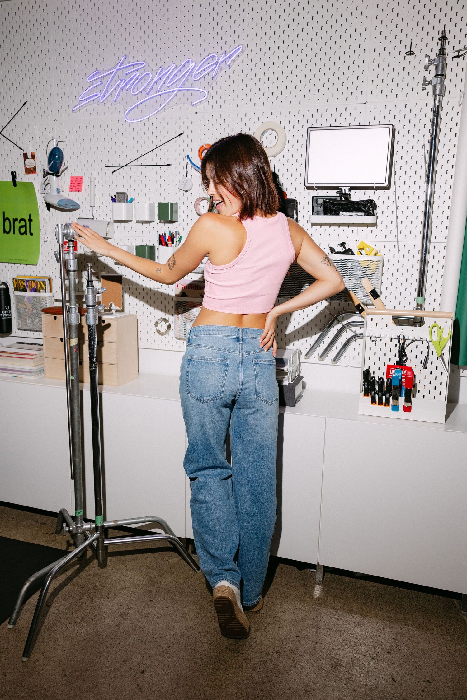 Artistic photo series showing playful movement against studio wall with neon signage.