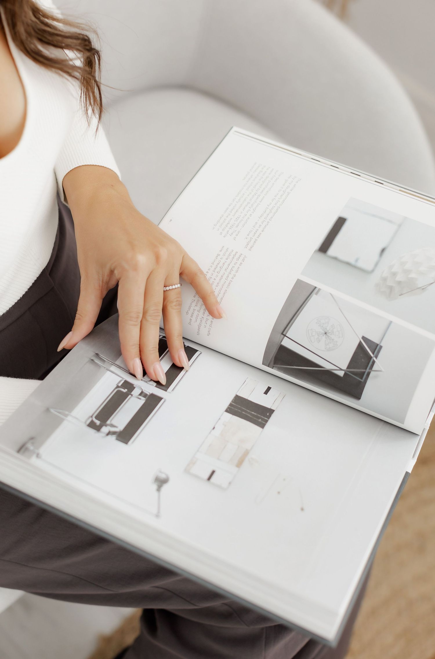Person browsing through interior design book showing minimalist spaces.
