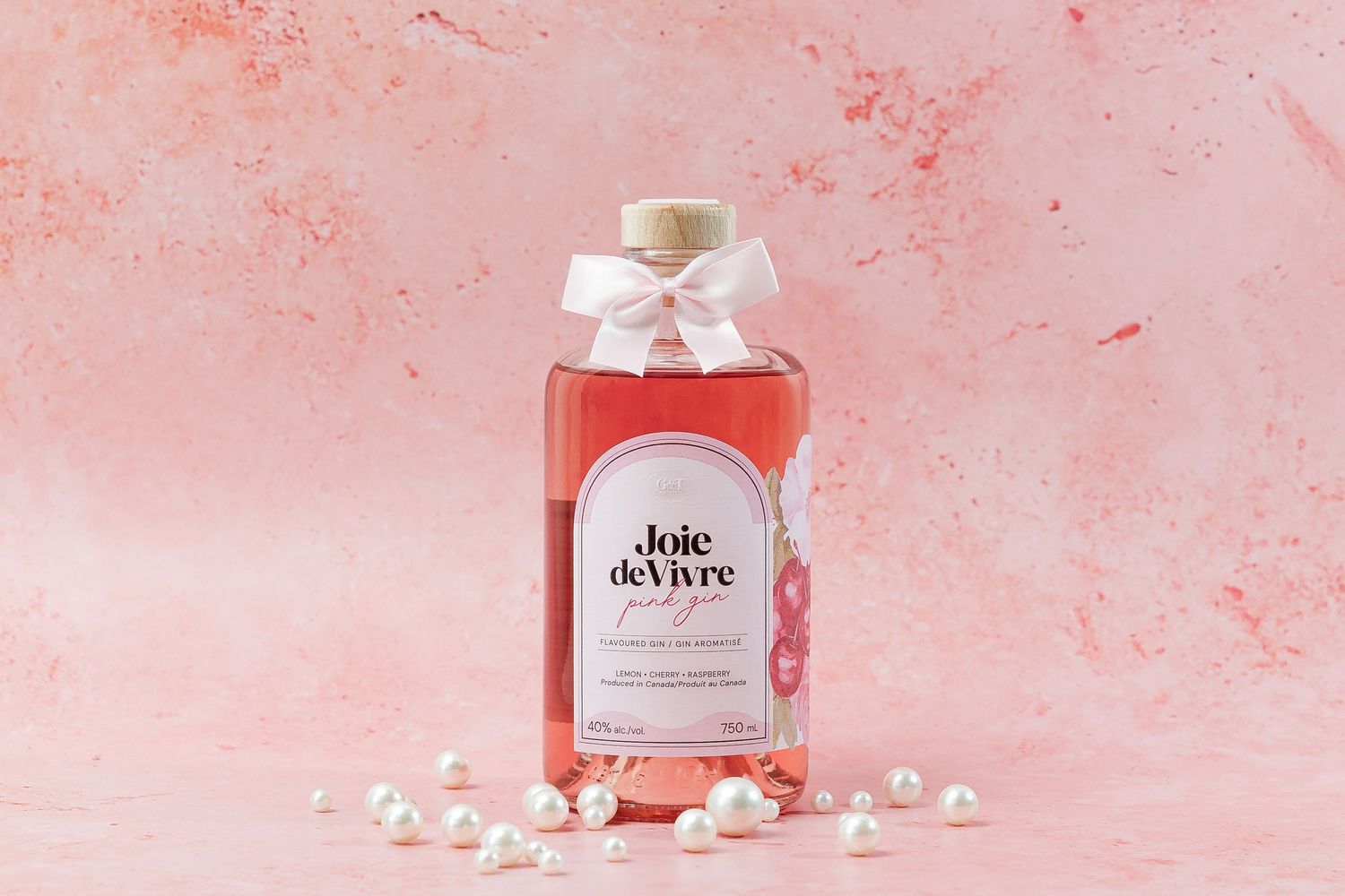 Stylish pink wine bottle display with pearls and bow accents.