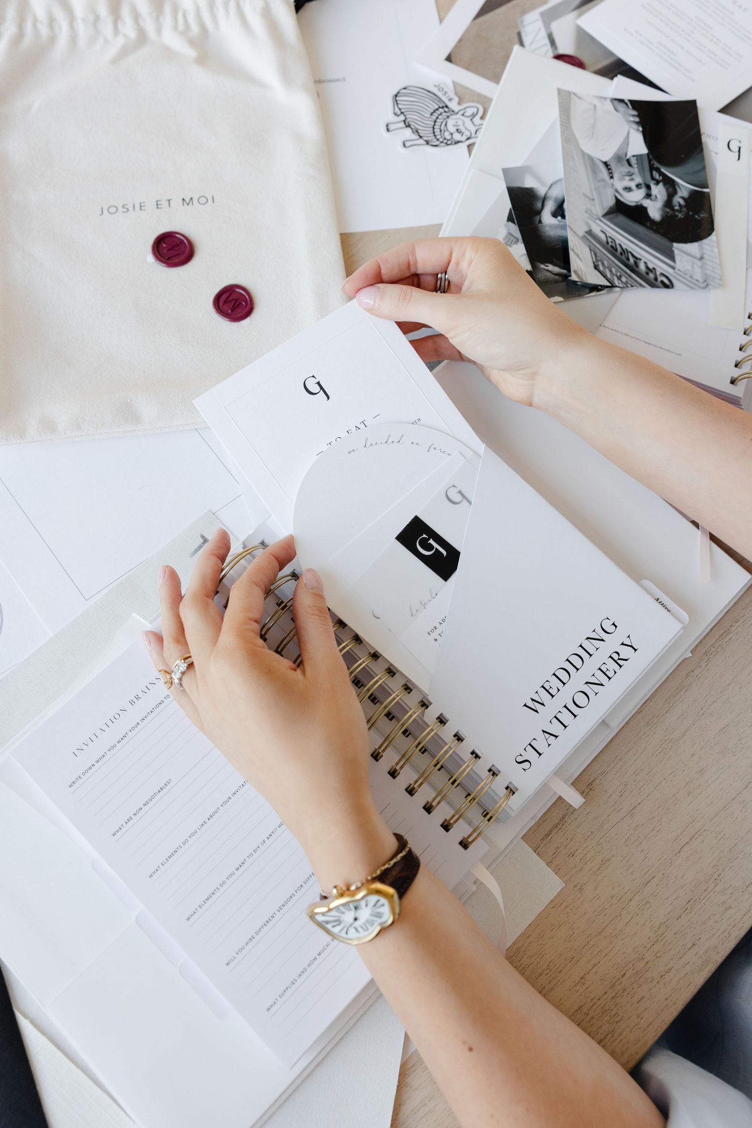 Close-up of hands working with minimalist white stationery and documents on desk.