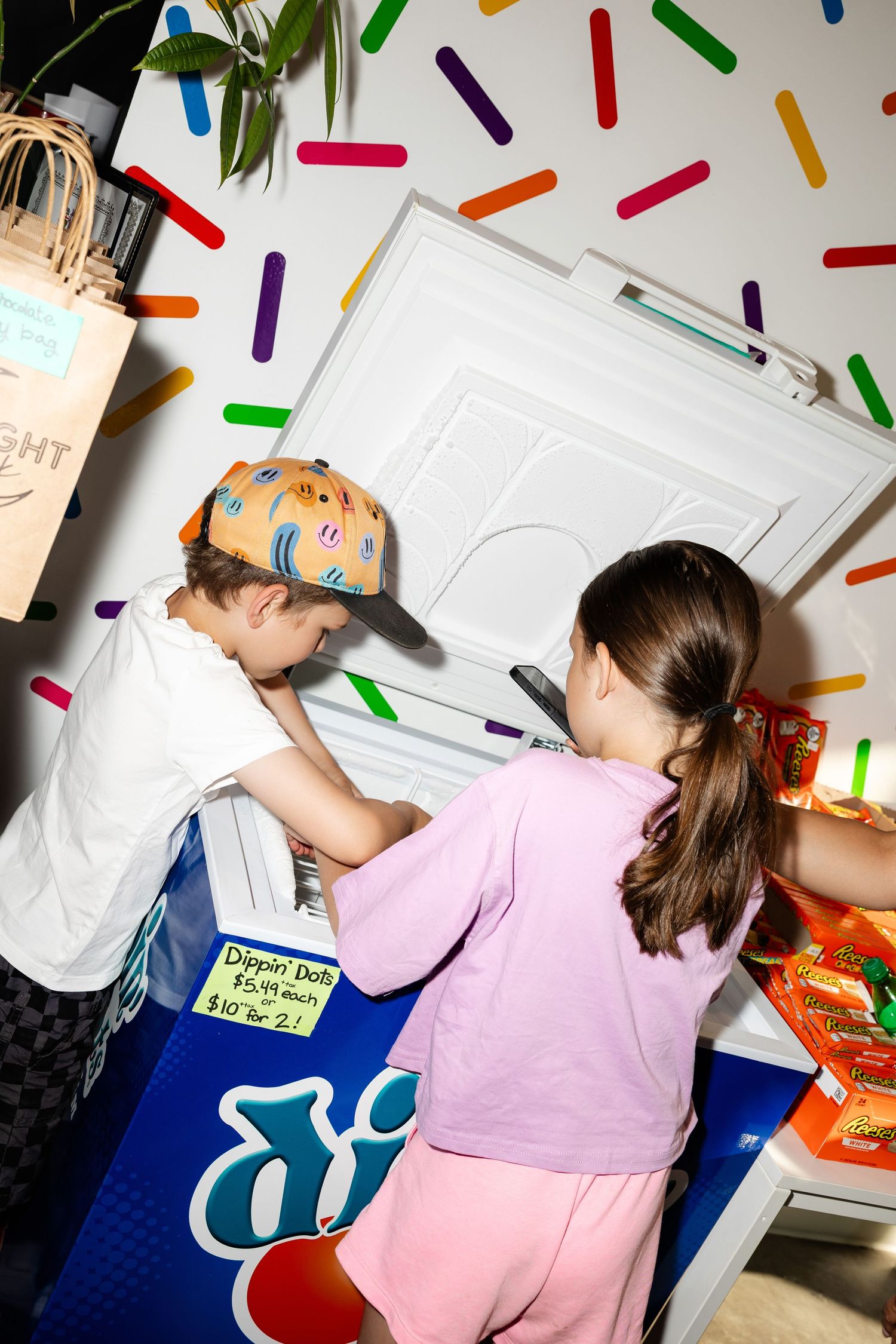 Children reaching for snacks against a wall decorated with colorful stripes.