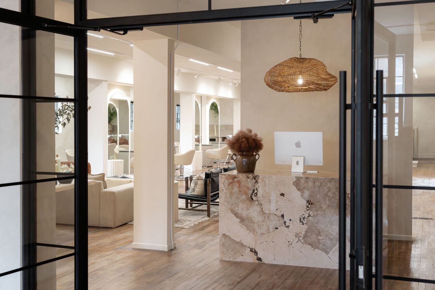 Modern salon entrance with black-framed glass doors and marble reception desk.