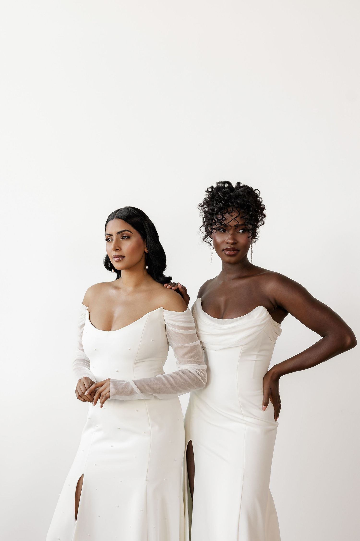 Models showcasing sleek white wedding dresses in a minimalist studio setting.