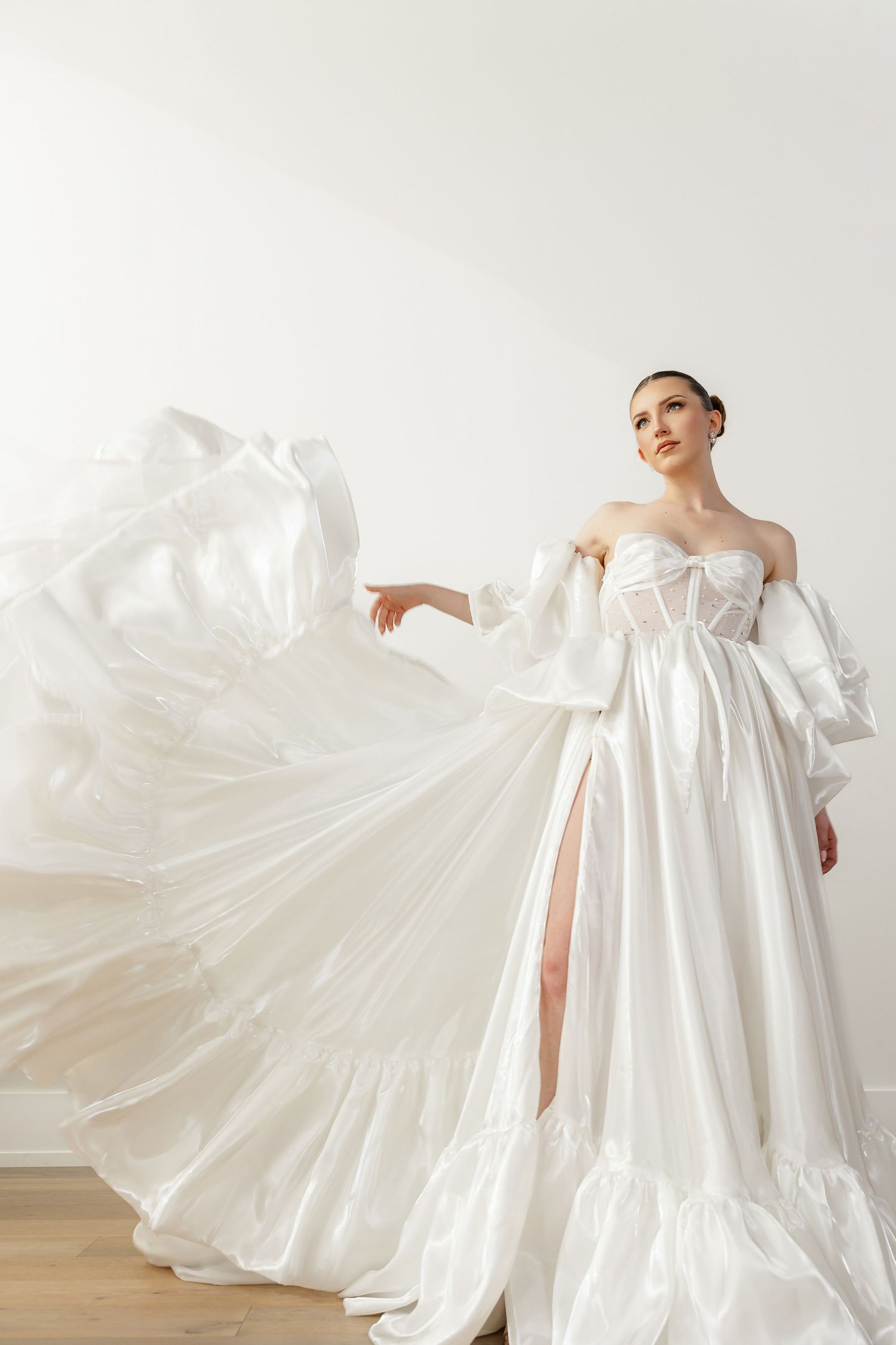 Flowing white empire waist wedding gown with dramatic train captured in ethereal studio shots.