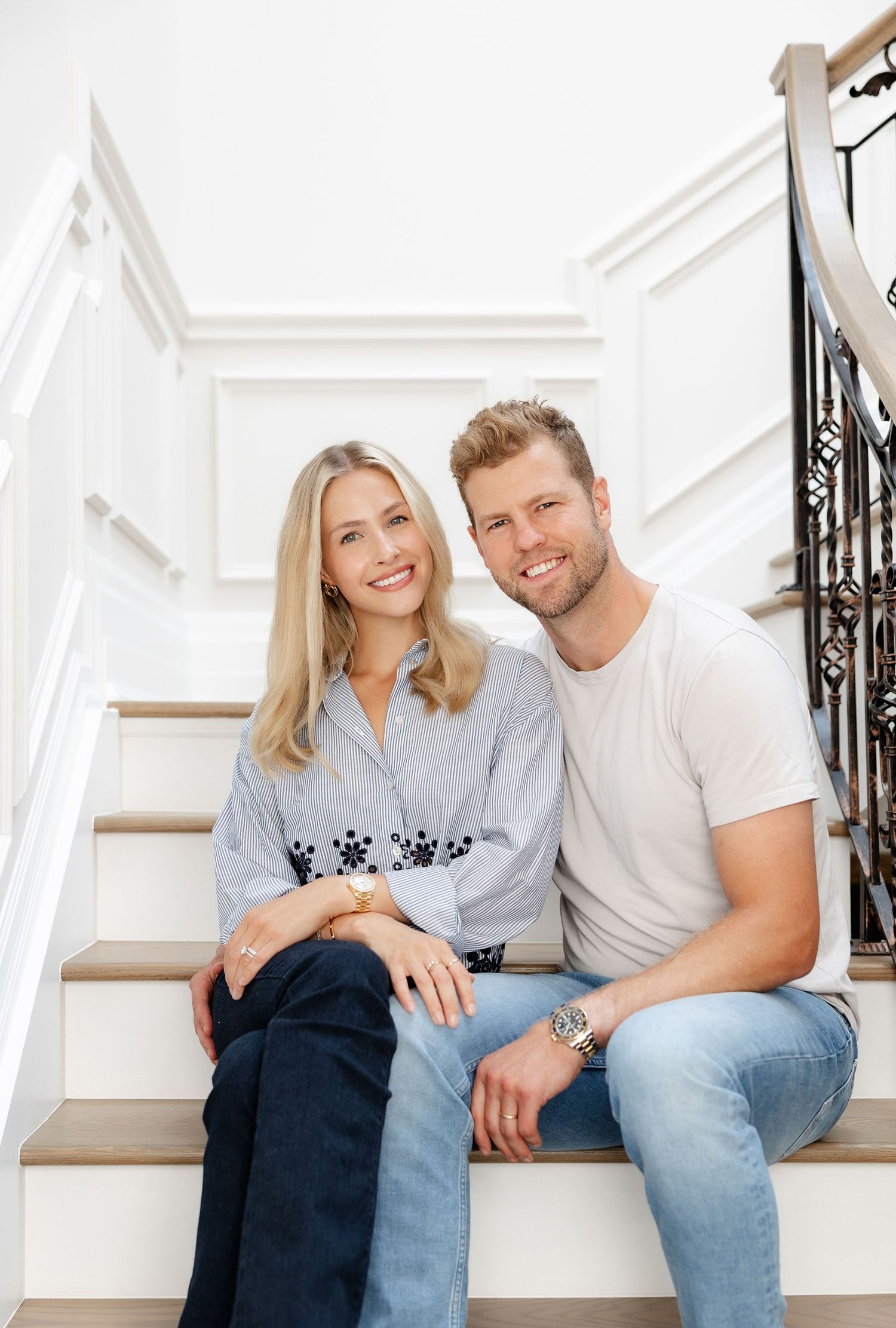 Couple sitting together on white staircase wearing coordinated casual outfits.
