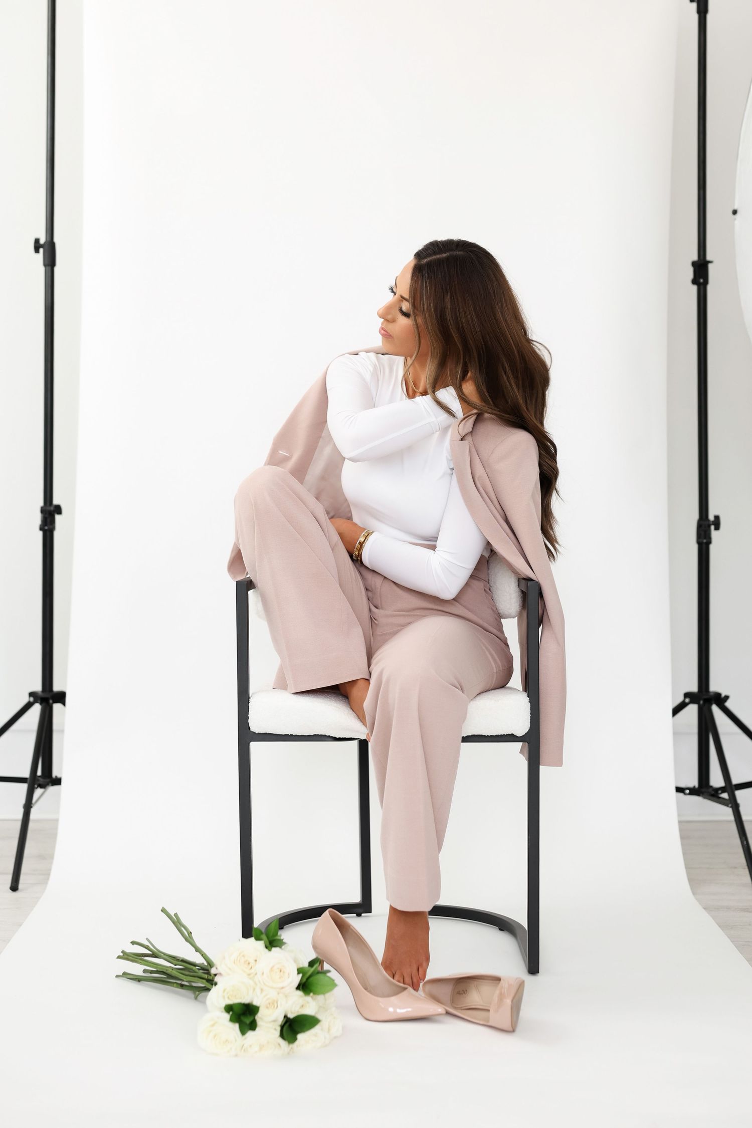 Fashion photo featuring pink blazer and pants with white flowers on floor.
