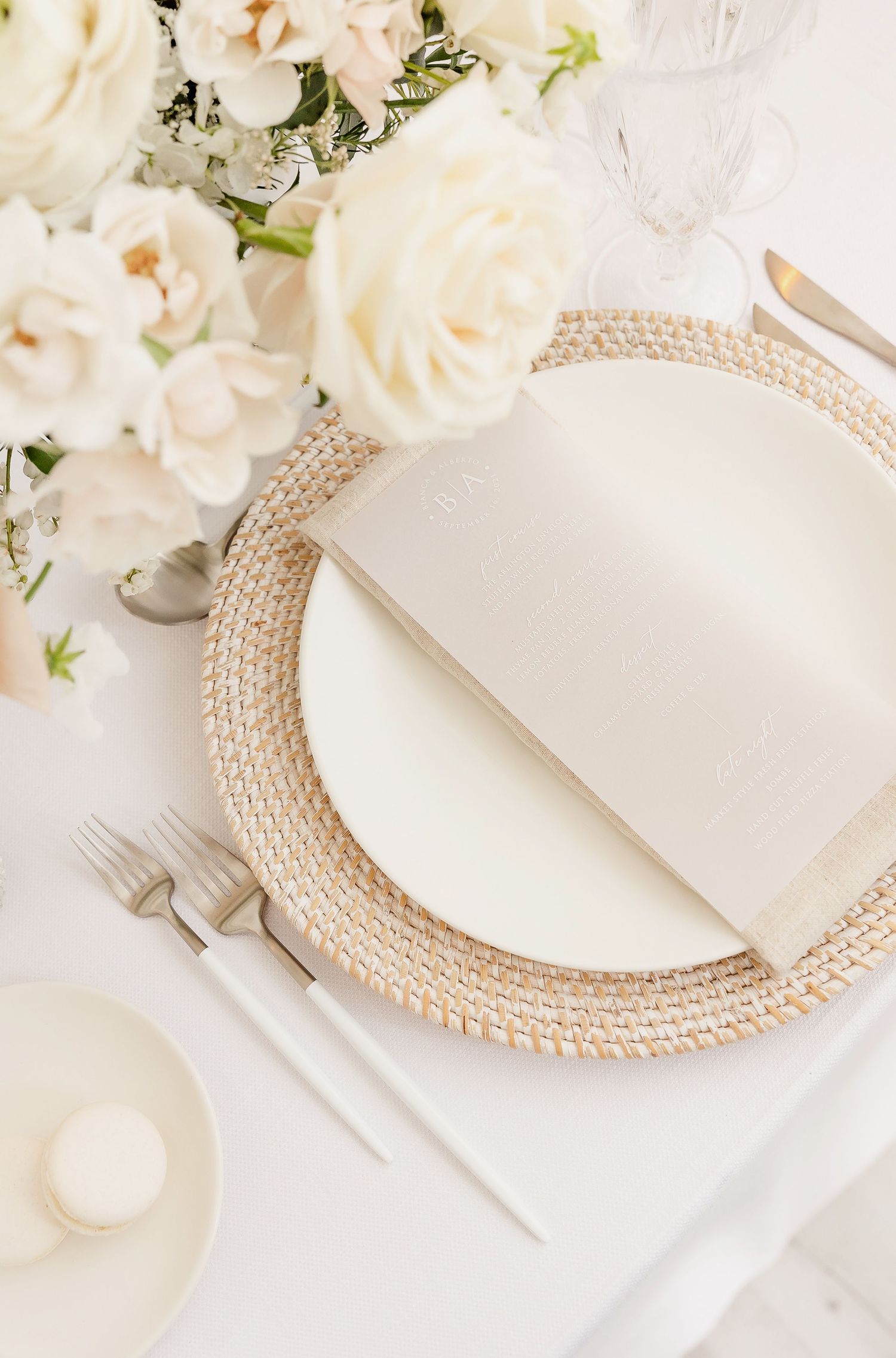 White place settings with pearl charger plates and ivory floral centerpieces.