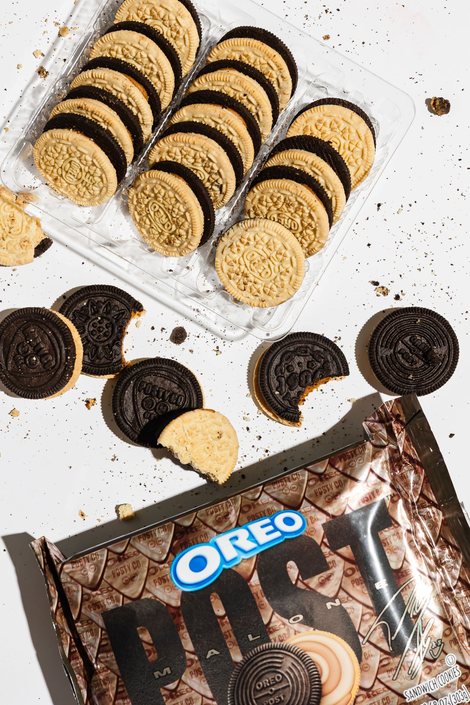 Golden and chocolate Oreo cookies arranged with product packaging on white surface.
