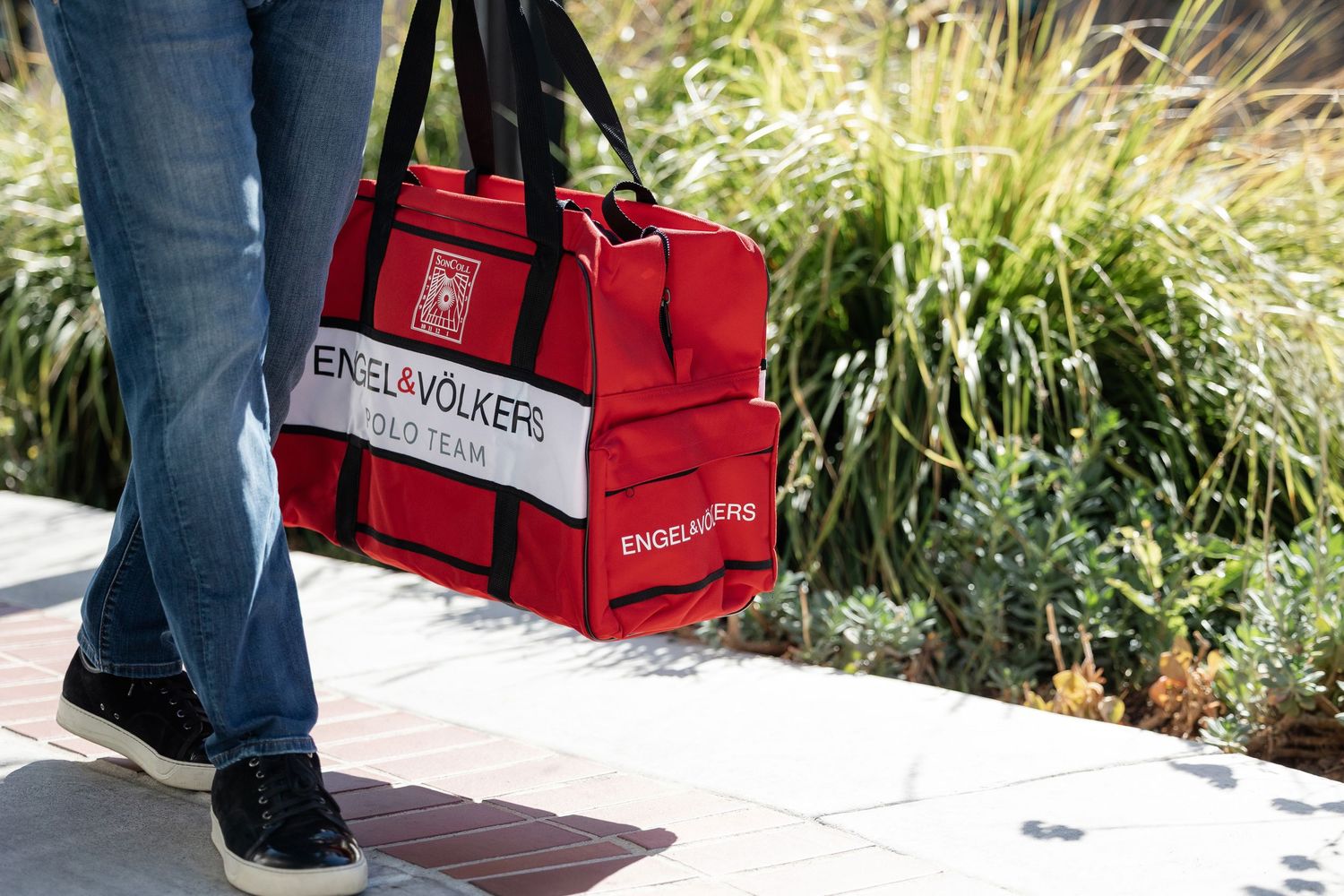 Red shopping bags placed on outdoor walkway with decorative grass in background.