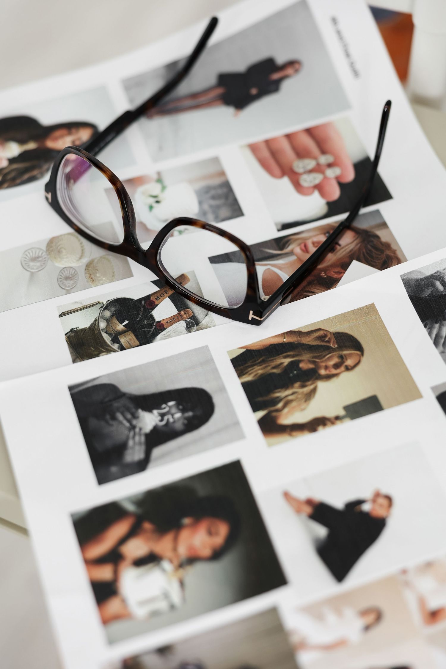 Collection of black and white photographs spread out on white surface with camera strap.