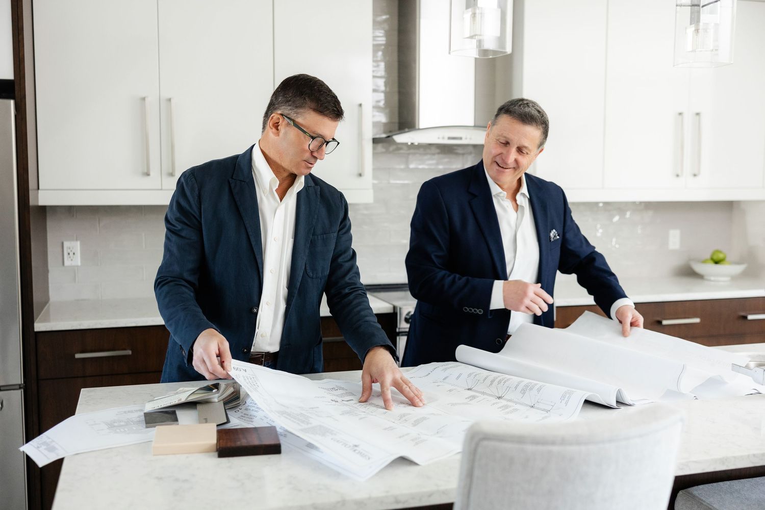 Two professionals discussing architectural plans in contemporary kitchen setting.