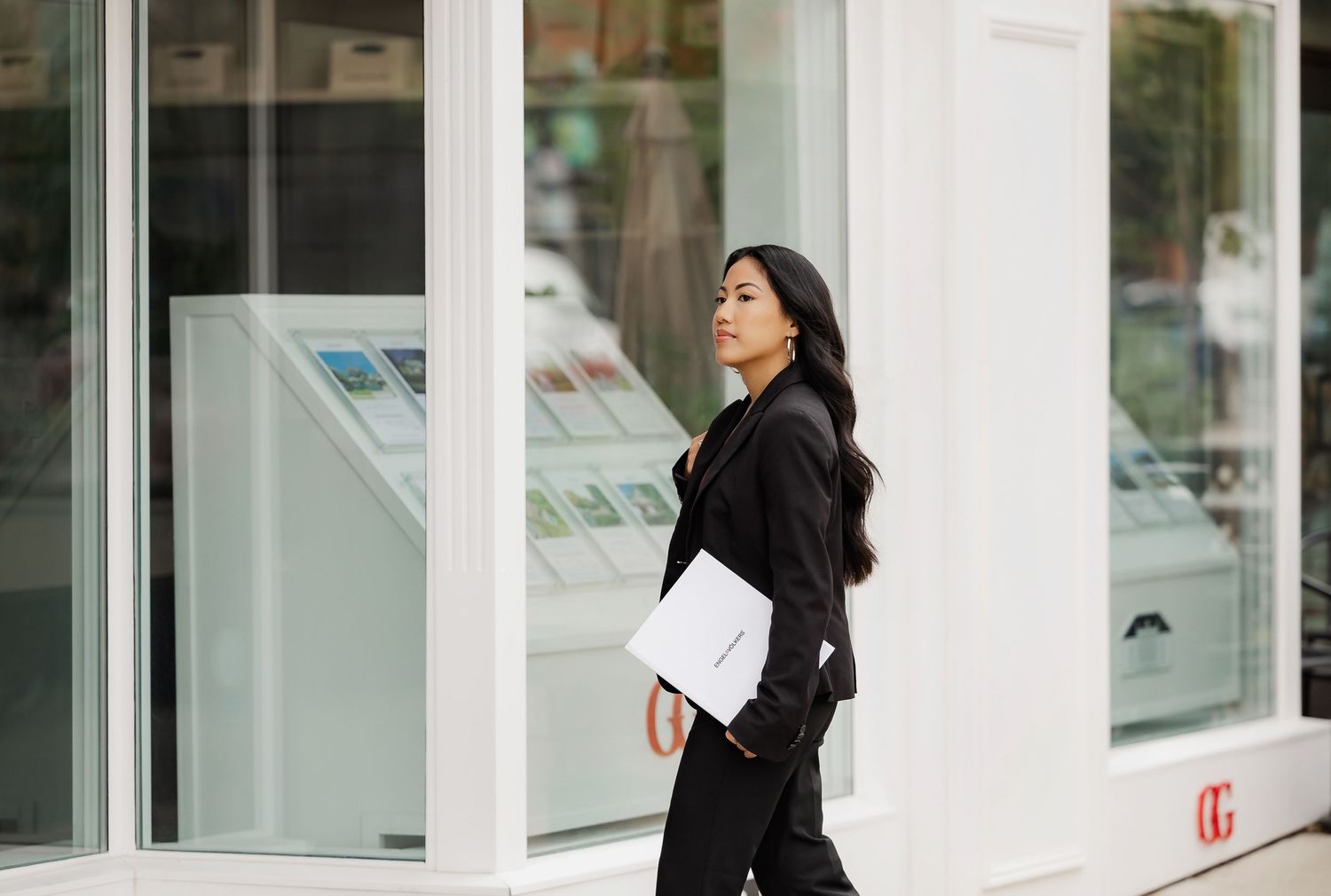 Professional walking past modern white office building exterior.