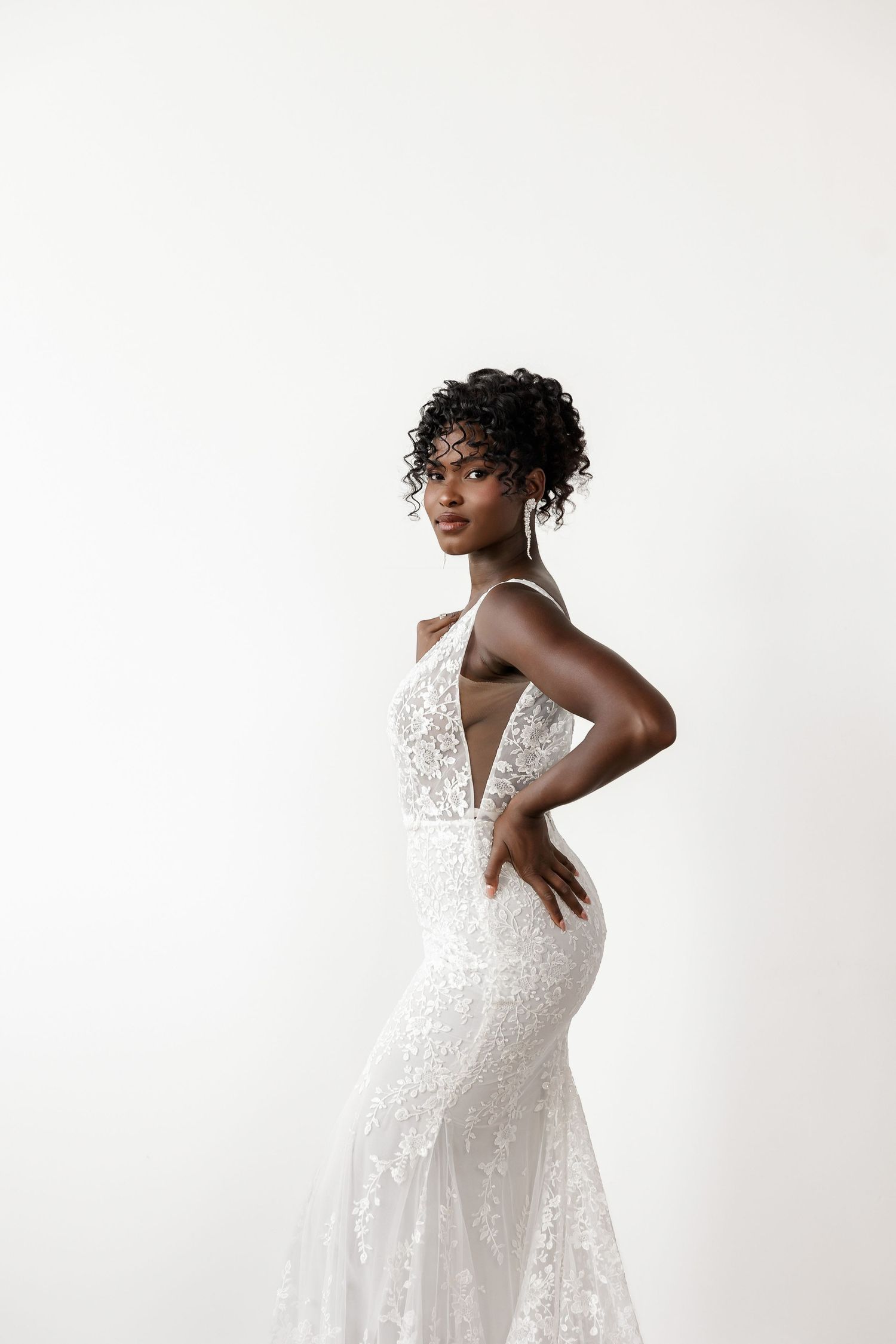 Delicate lace wedding gown with plunging neckline and intricate details shown in profile.