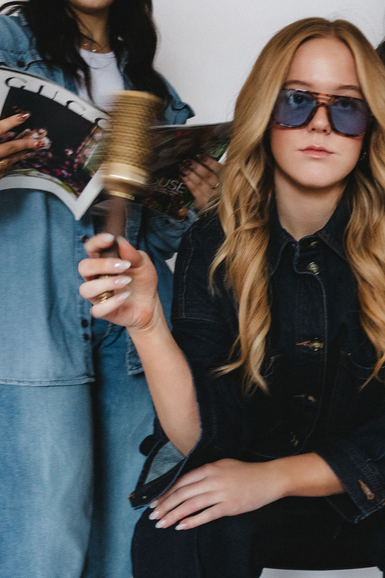 Stylish fashion photoshoot with denim and black clothing against white backdrop.