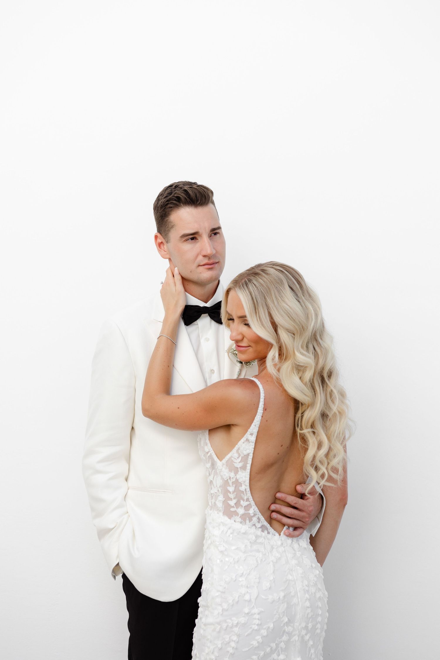 Intimate wedding portrait against white background showing tender moment between newlyweds.