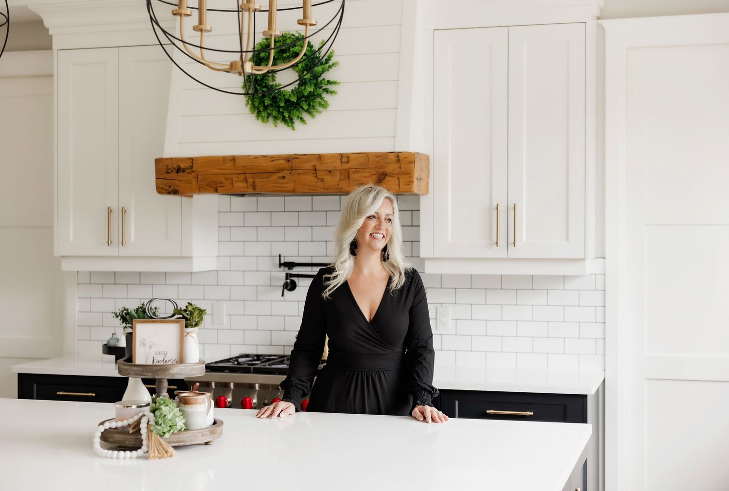 Modern white kitchen with subway tile backsplash and rustic wooden beam accent.