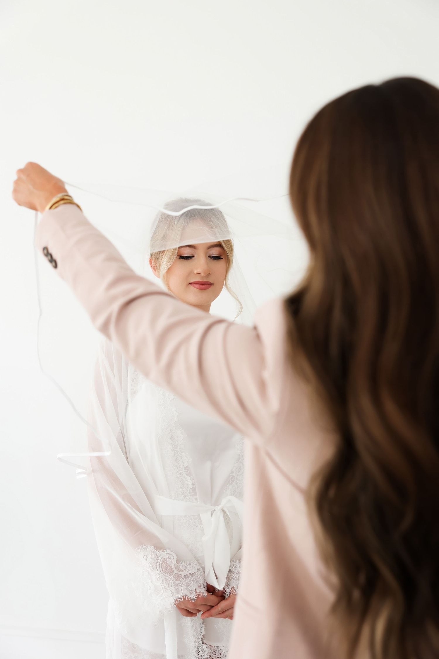 Styling session showing wedding attire preparation with two people against white background.