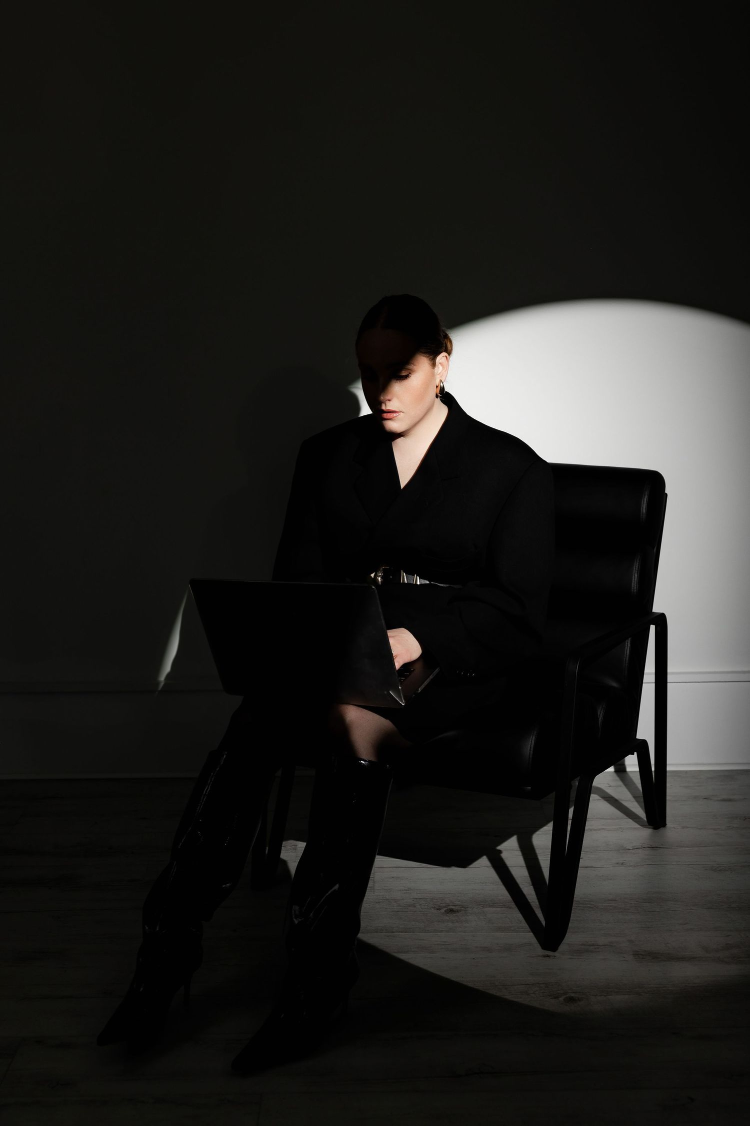 Moody low-key portrait in chair with dramatic spotlight effect.