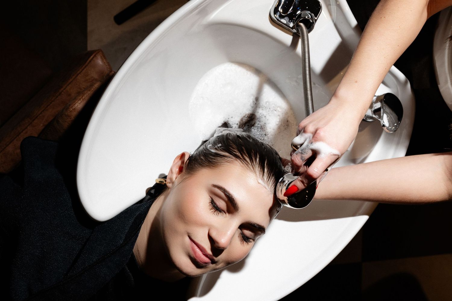 Hair washing process at salon sink with professional equipment.