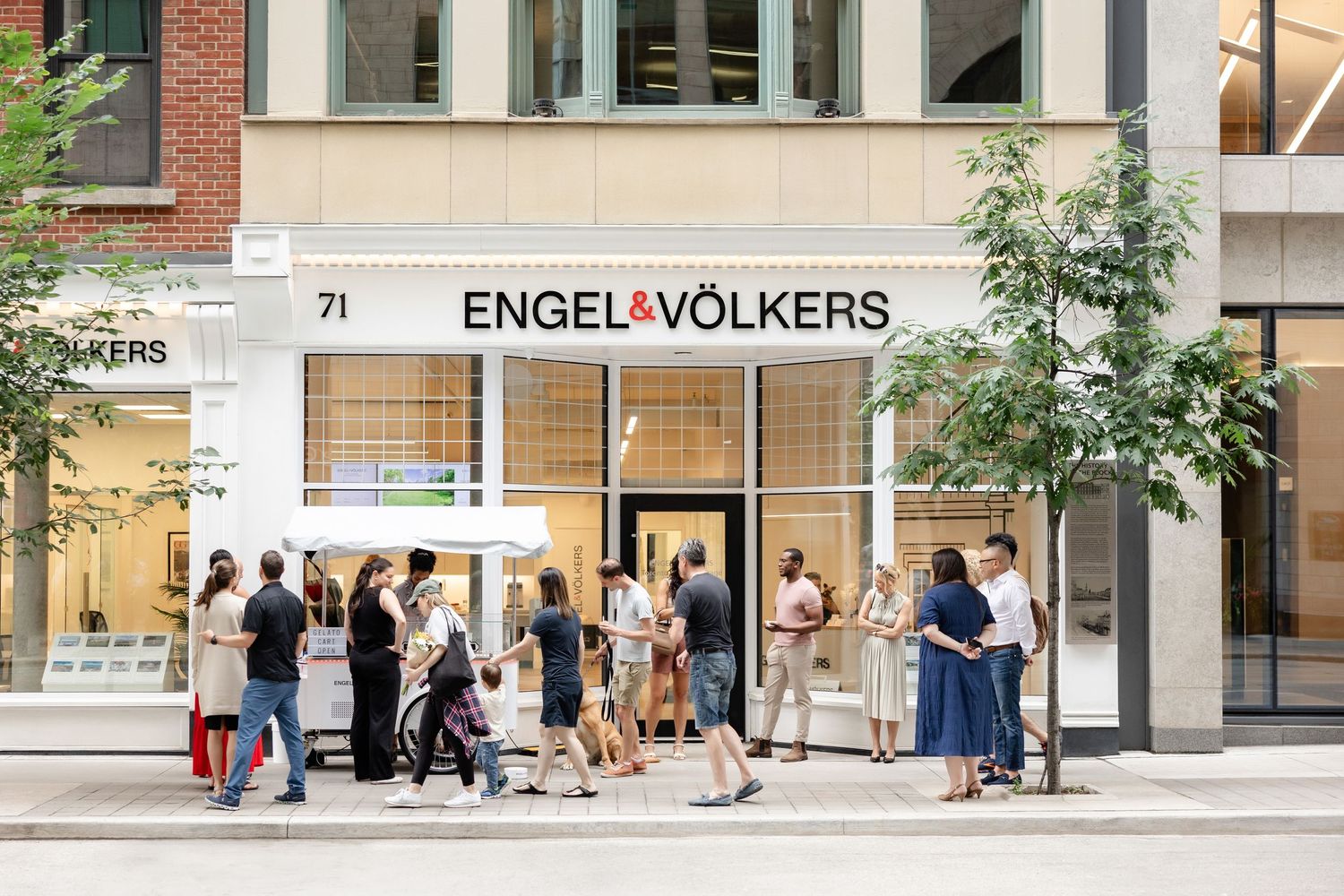 Exterior view of Engel & Volkers real estate office storefront with pedestrians walking by.