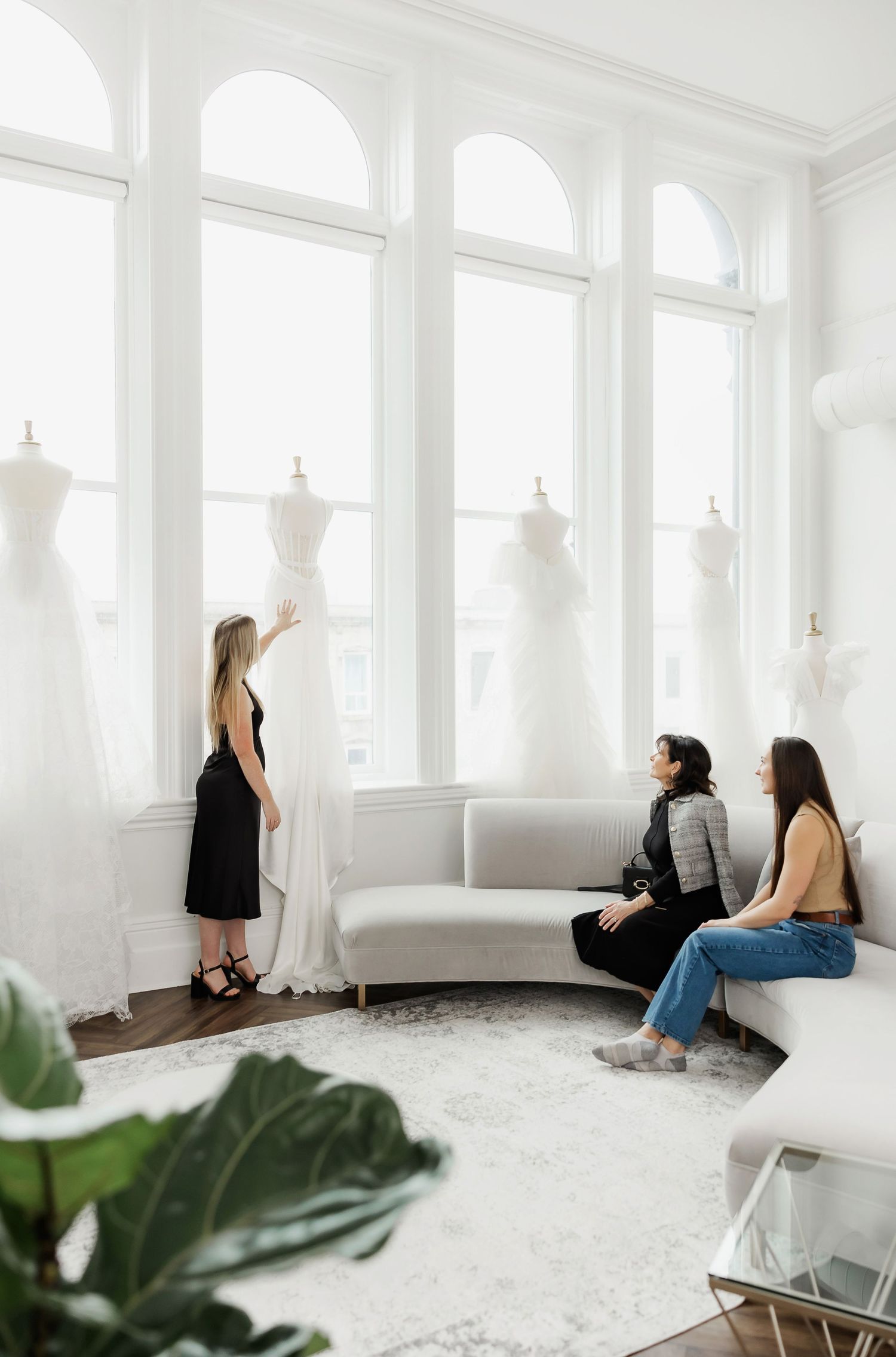 Modern bridal boutique interior with white walls, hardwood floors and wedding gowns displayed.