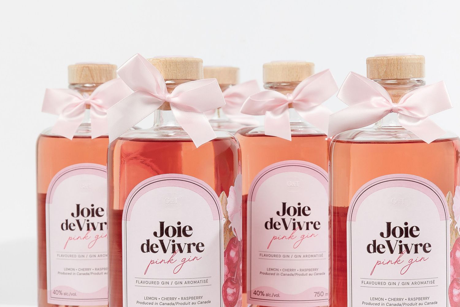 Row of pink wine bottles with matching labels and delicate white ribbon bows.