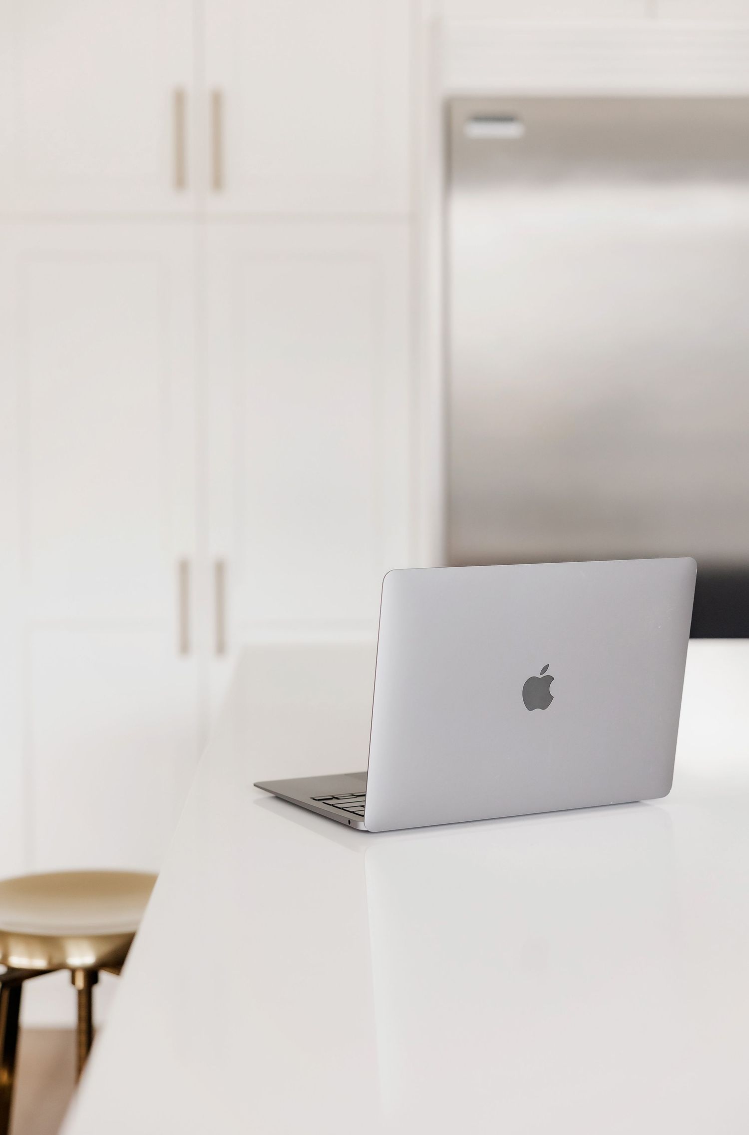 Silver MacBook laptop on white counter in minimal modern setting.