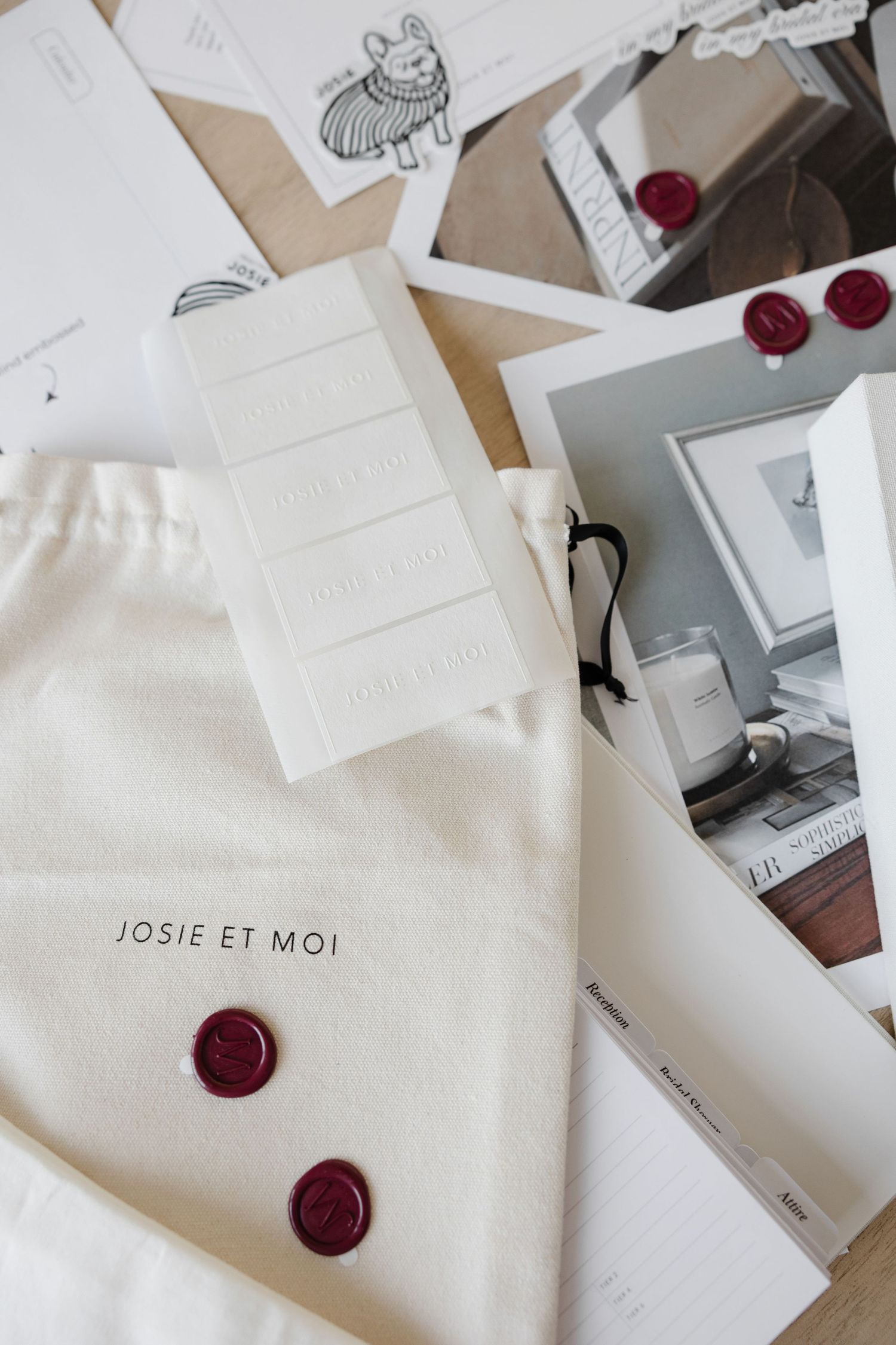 Branded fabric pouch with Josie et Moi text and red wax seals on wooden surface.