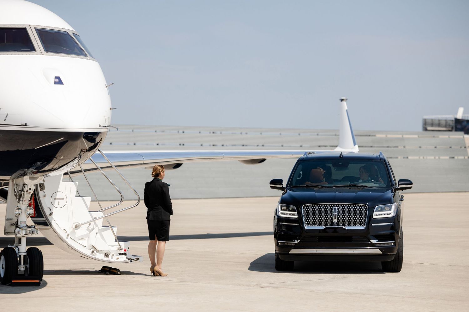 Luxury vehicles parked beside private aircraft on sunny airport tarmac.