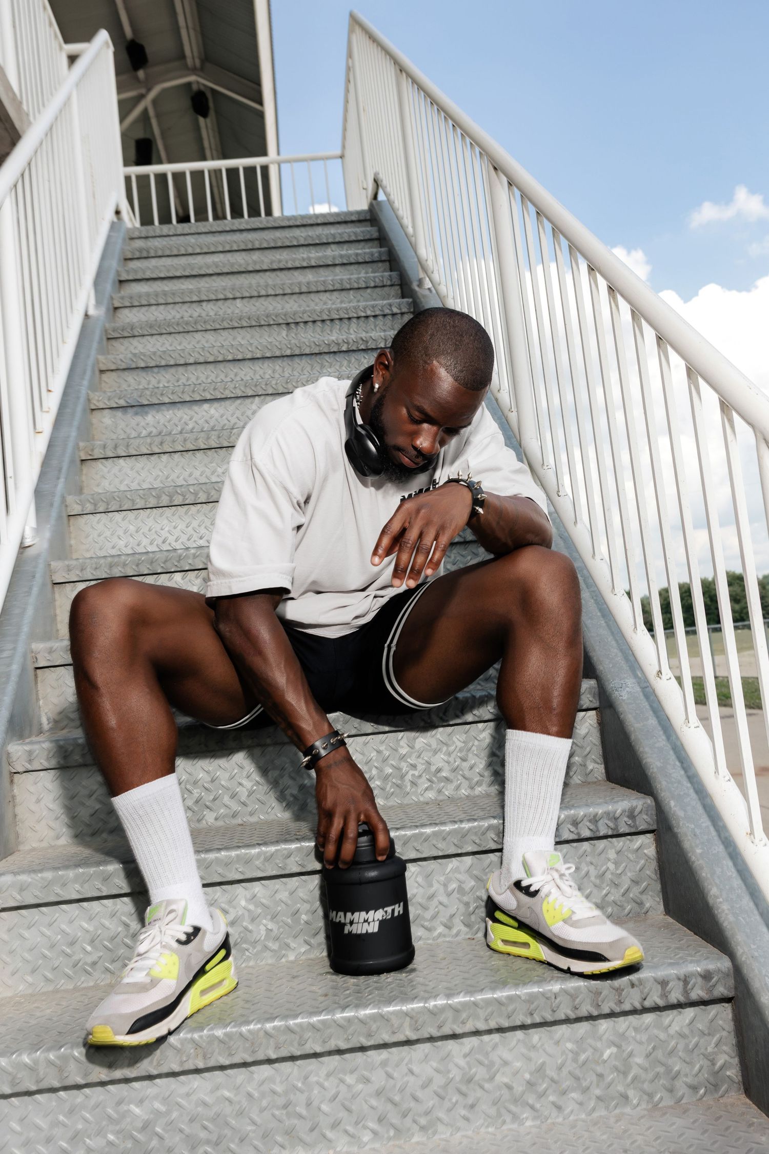 Athletic person resting on outdoor metal staircase wearing bright yellow sneakers.
