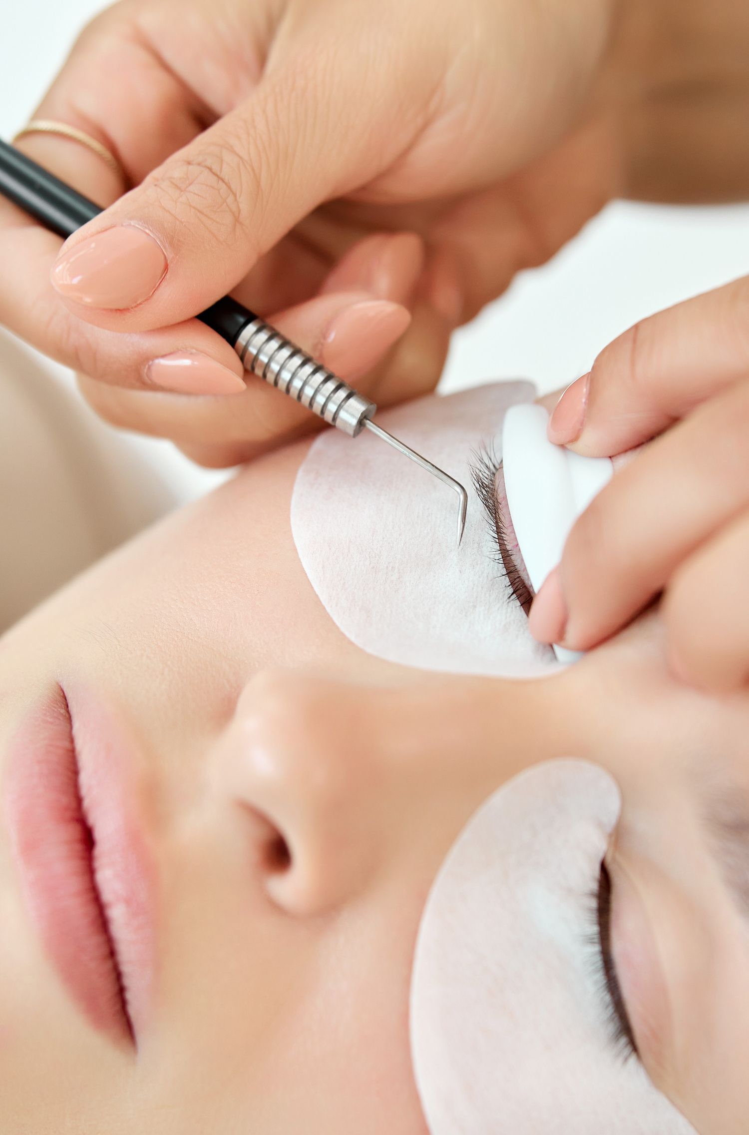 Close-up of professional eyelash extension application process on client.