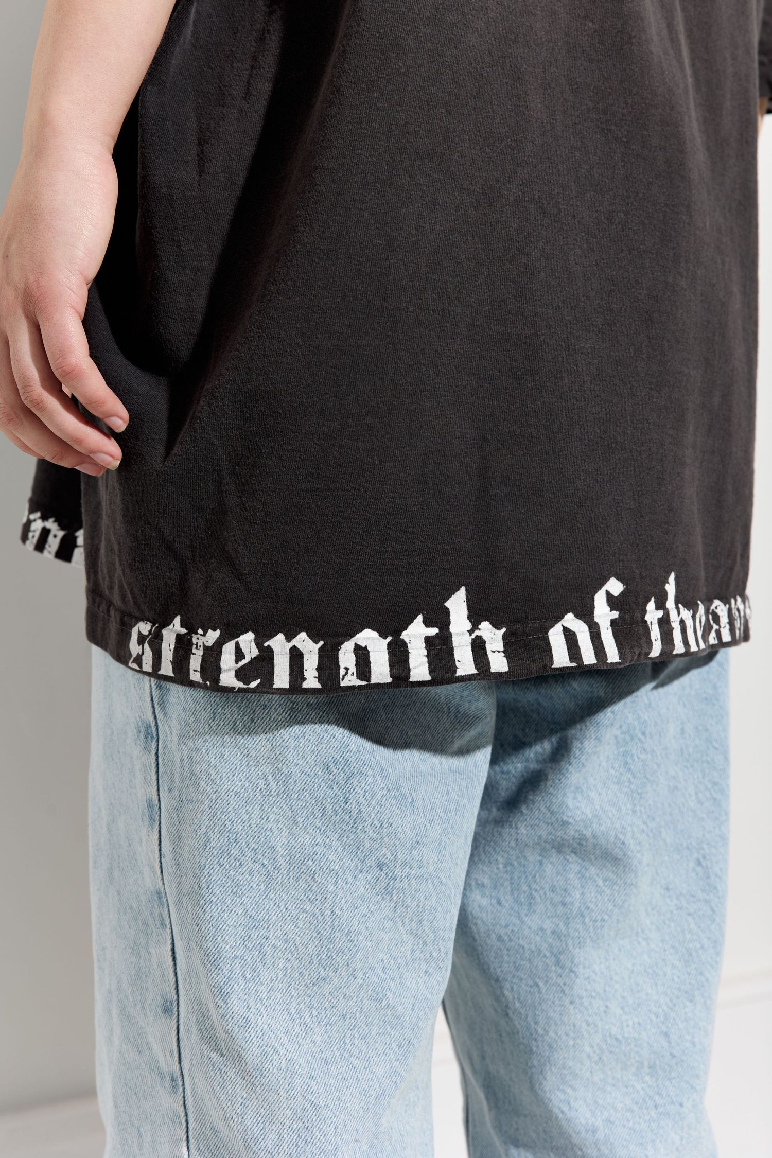 Detail shots of black Mammoth t-shirt text paired with light wash denim jeans.